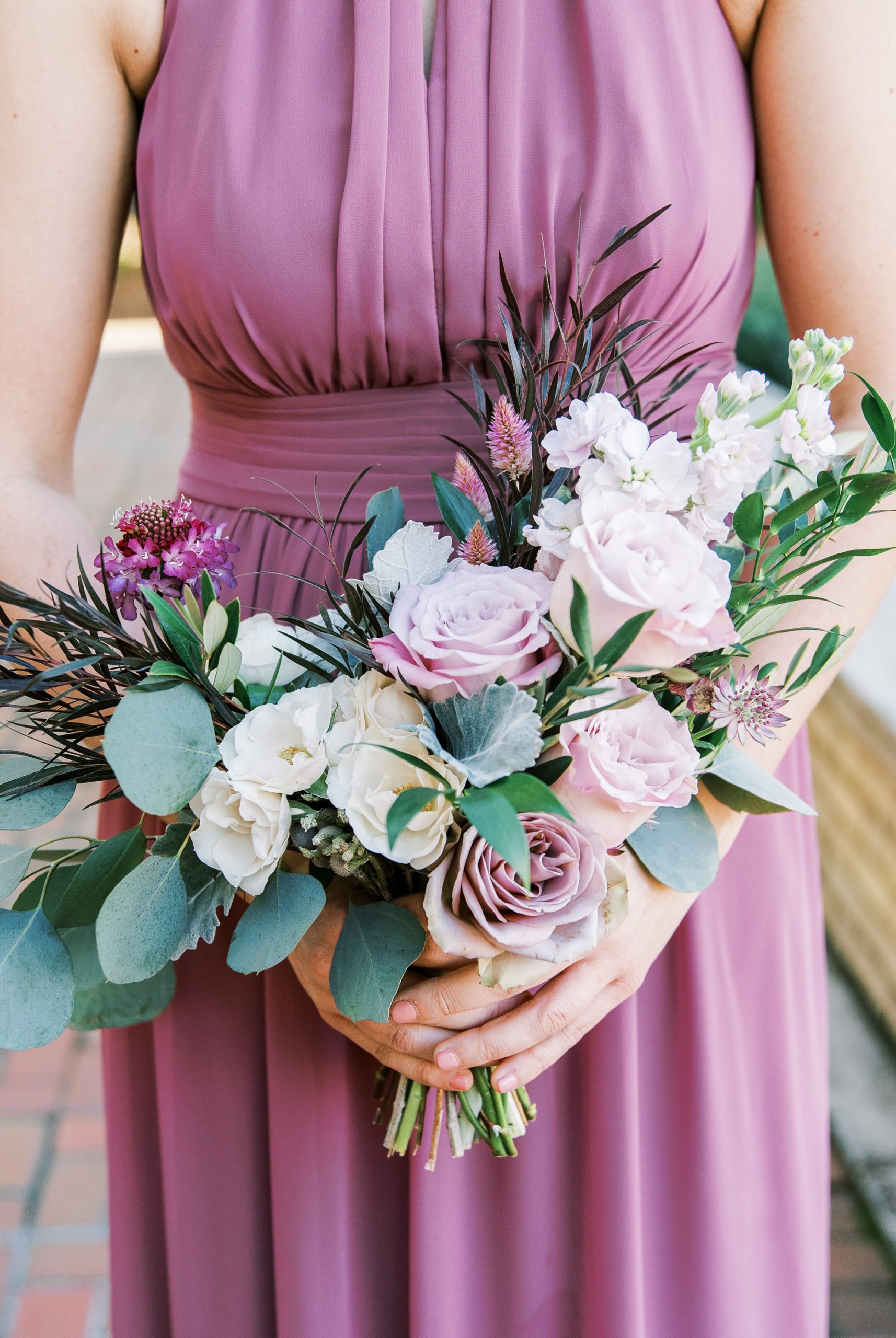 bridesmaid holds pink and ivory bouquet while wearing mauve fall wedding bridesmaid gowns