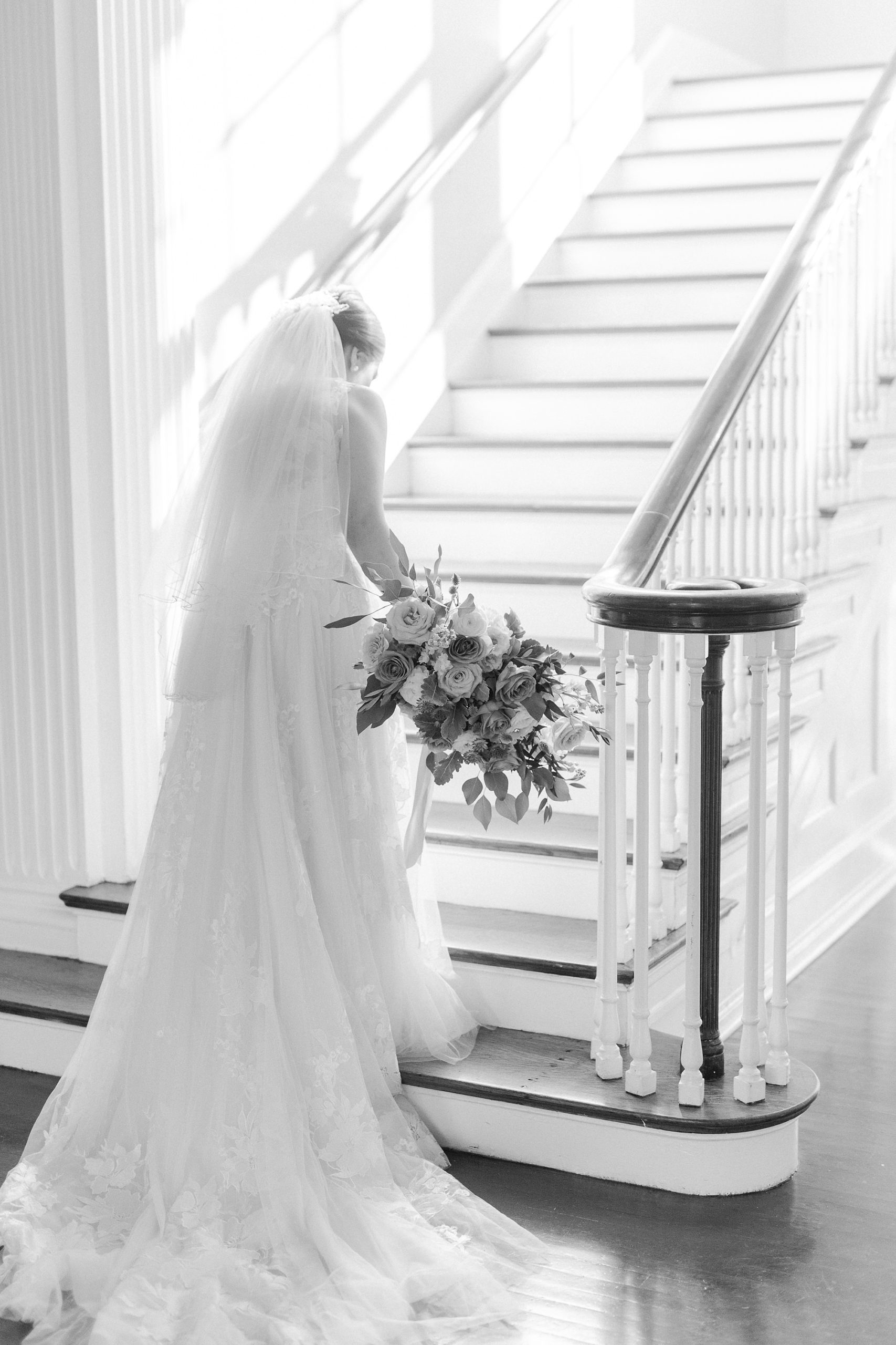 bride walks up staircase at Separk Mansion with veil trailing behind her