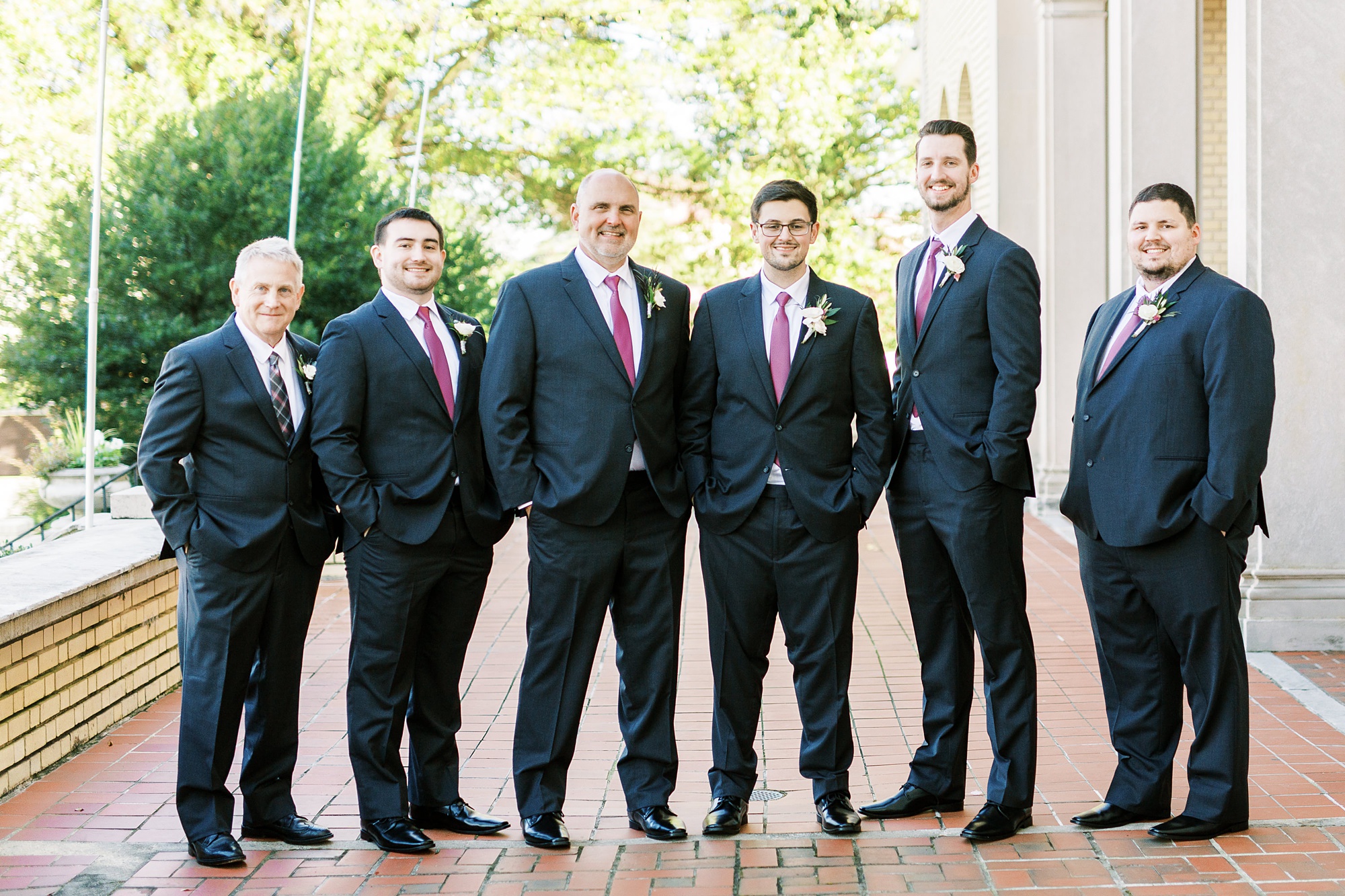 groom poses with five groomsmen in navy blue suits