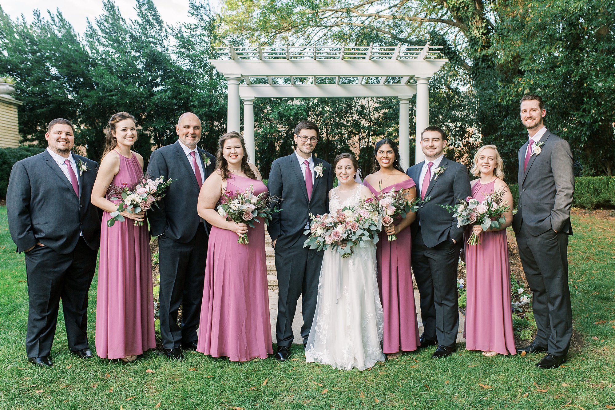 bride and groom pose with mauve fall wedding party