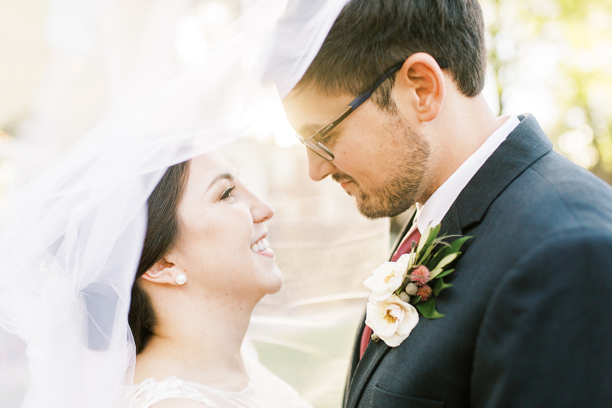 bride and groom smile under brides veil