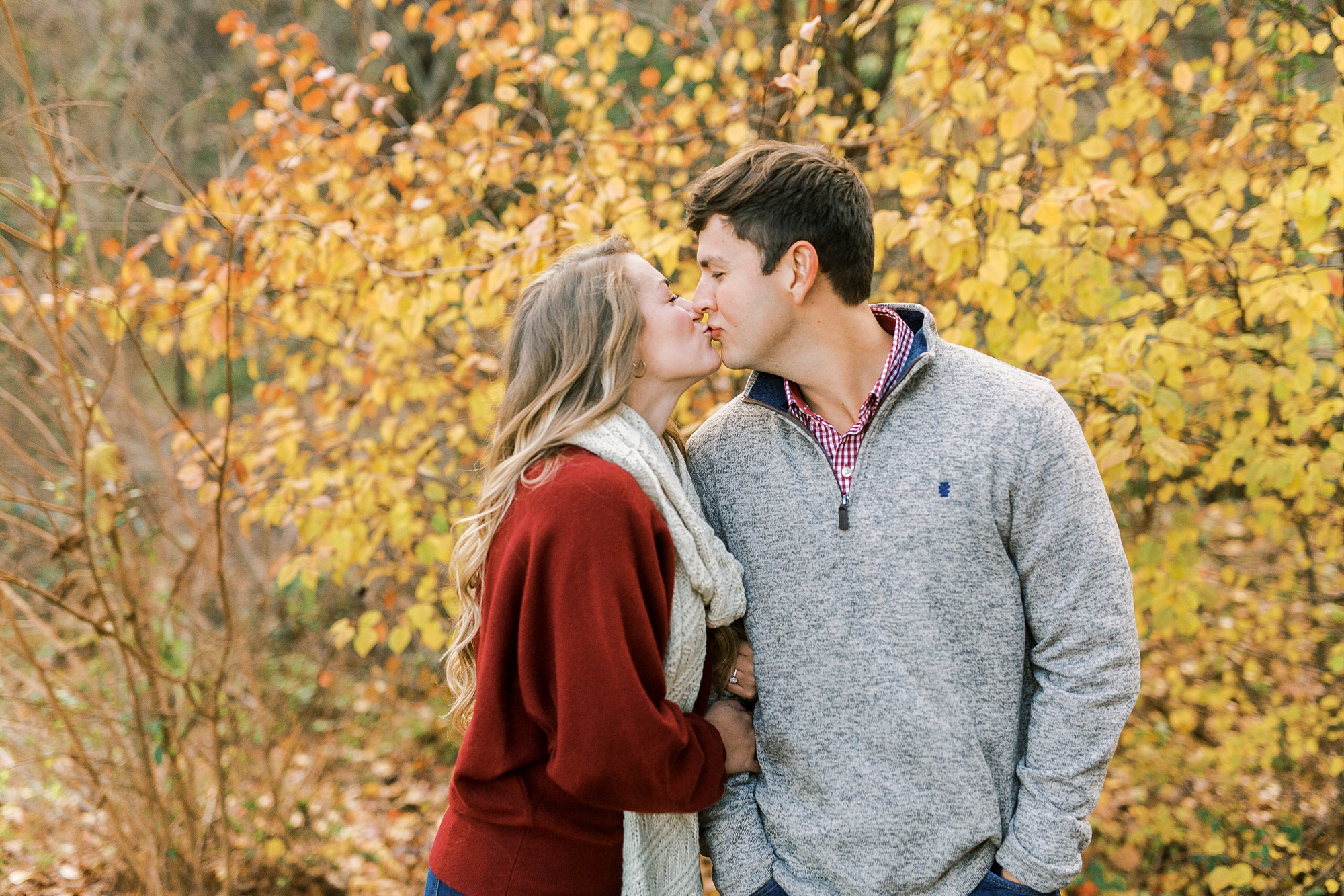 bride and groom kiss by yellow tree during fall engagement photos