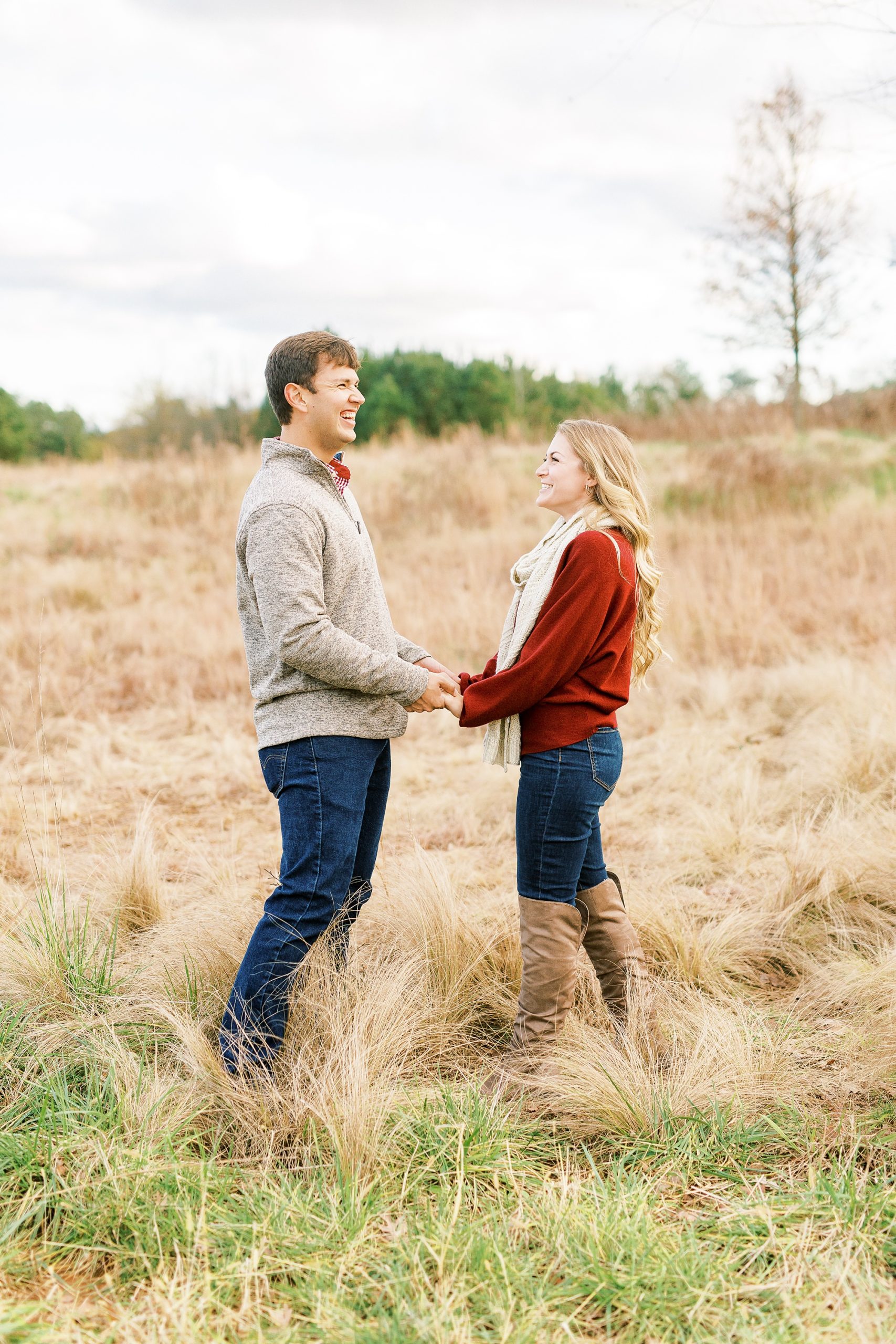 engaged couple holds hands standing in field