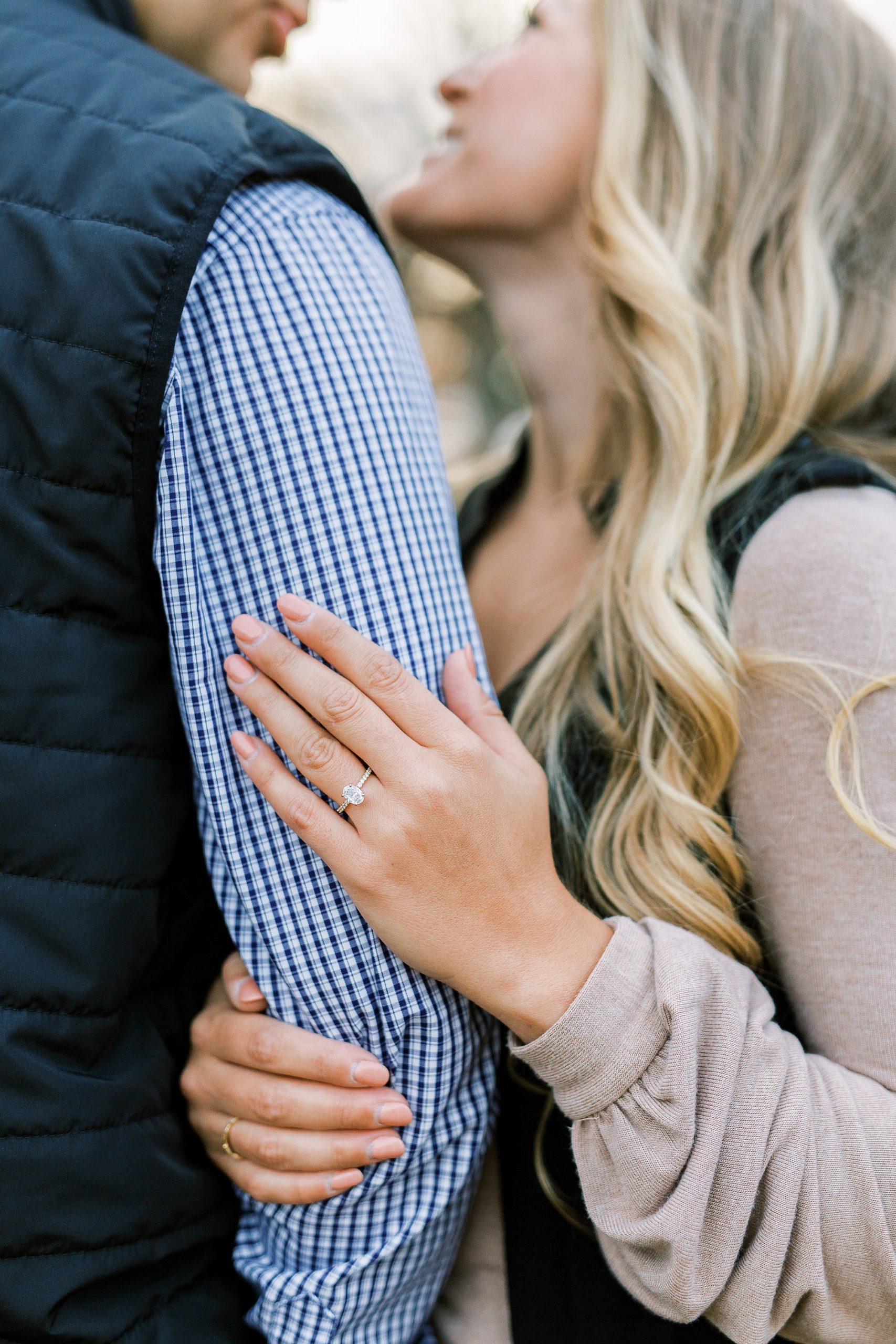 bride holds groom's arm showing off engagement ring