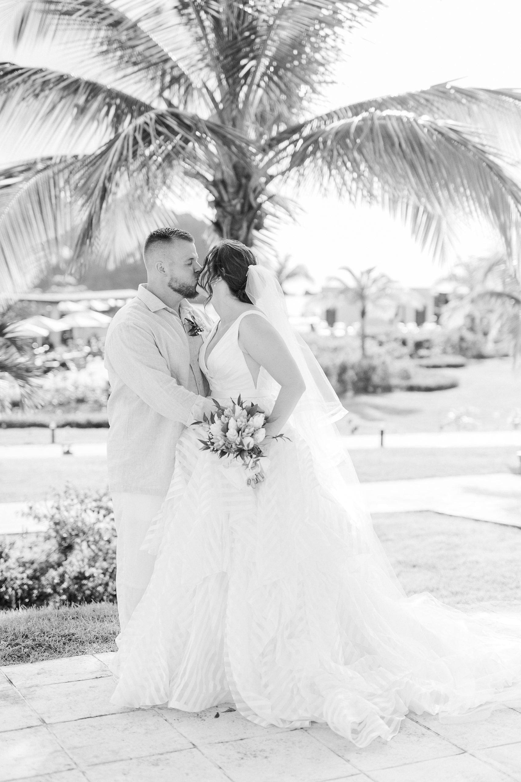 bride and groom kiss by palm tree in St Lucia