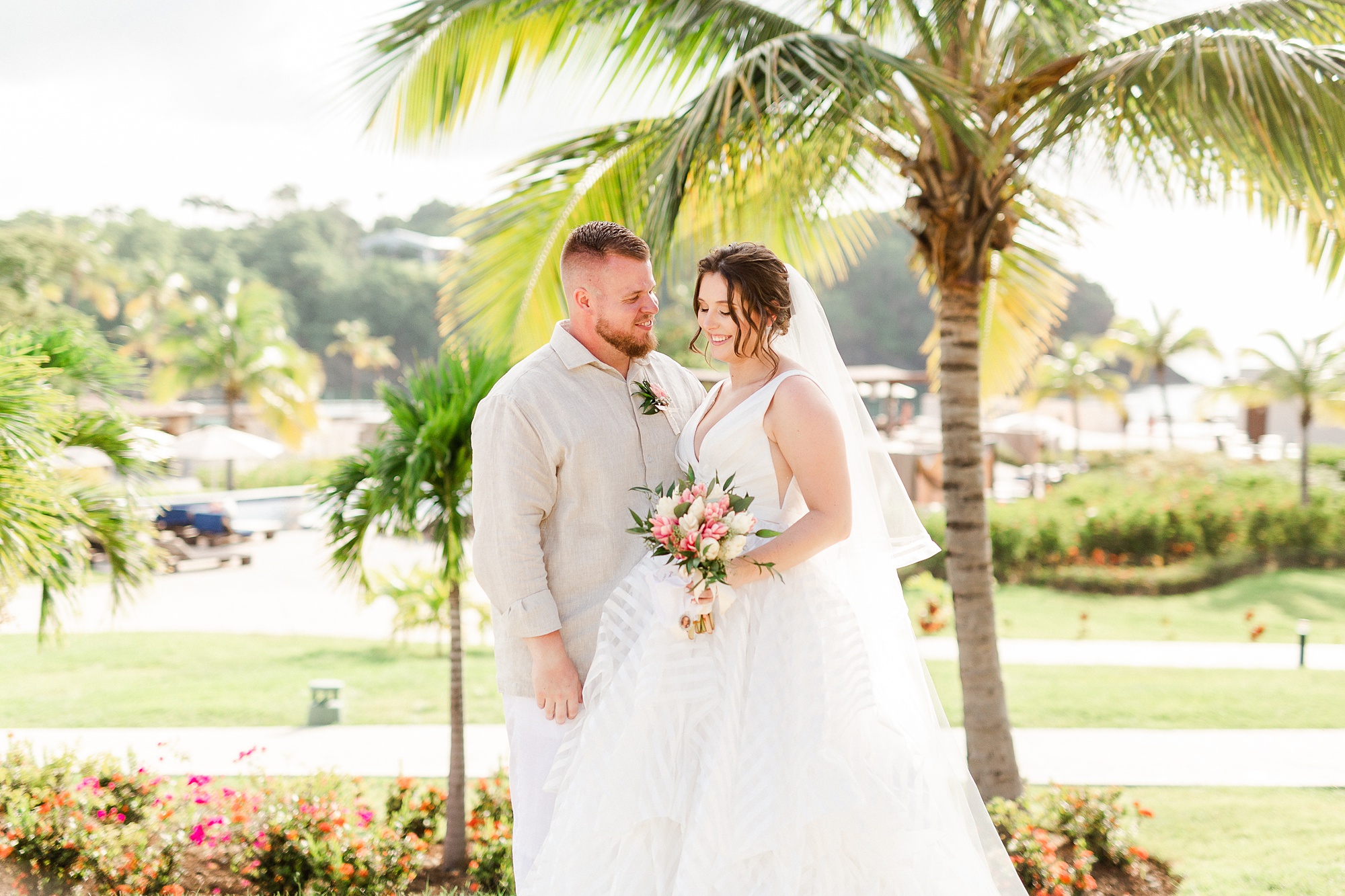 bride and groom pose by palm tree before St Lucia resort wedding
