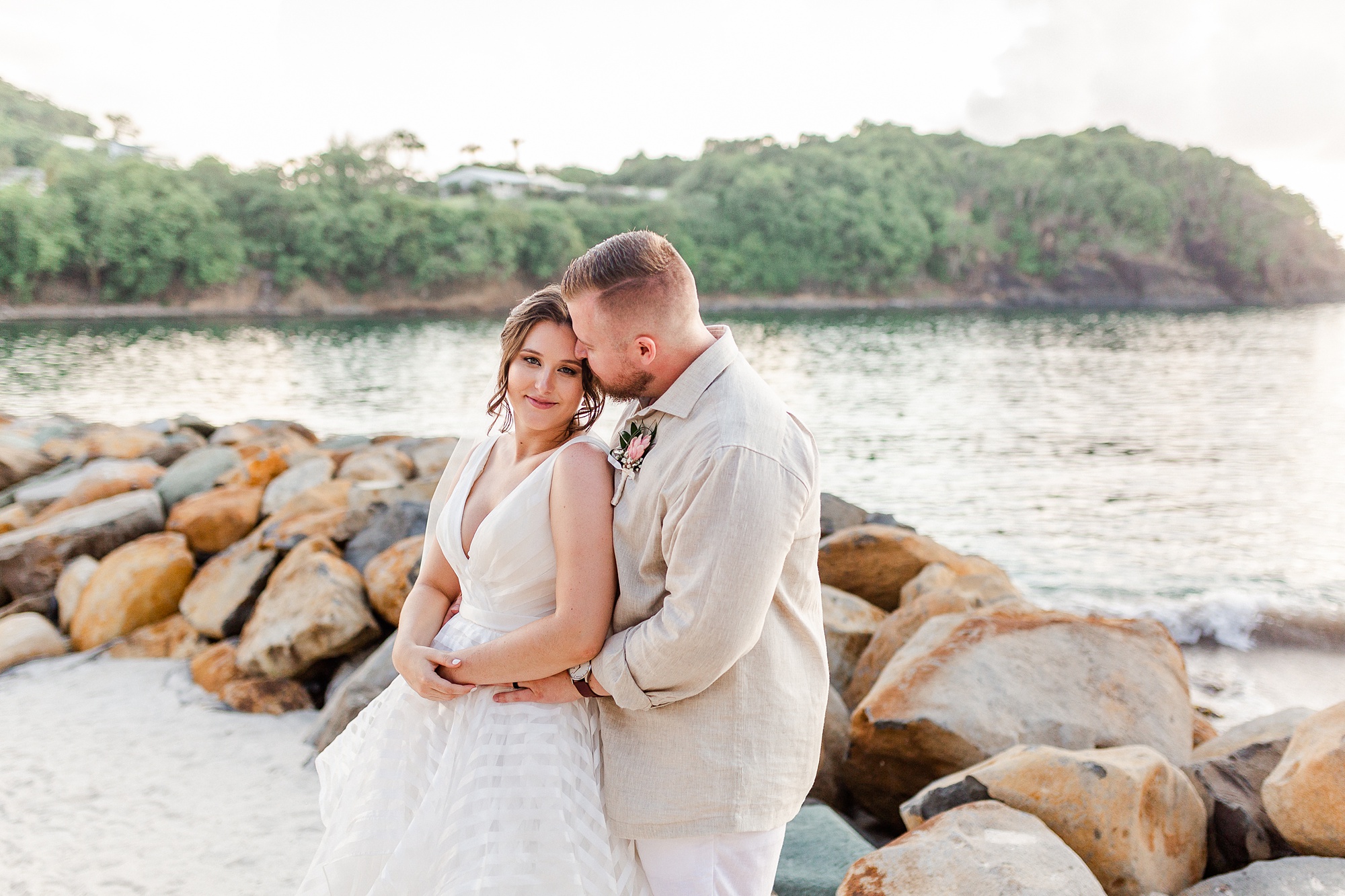 bride and groom kiss along rocks at St Lucia resort