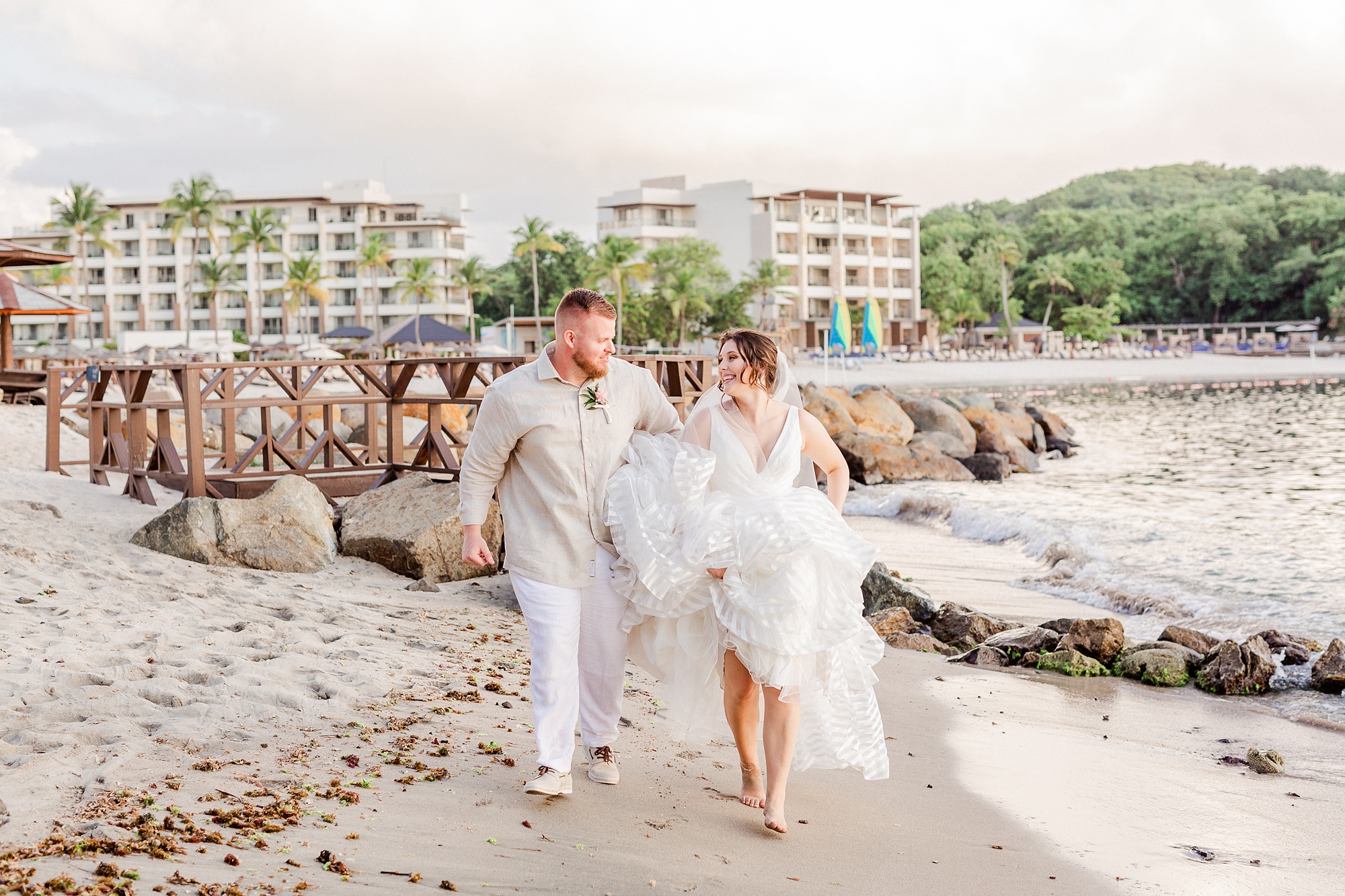 bride and groom walk along the beach at Royalton Resort in St Lucia