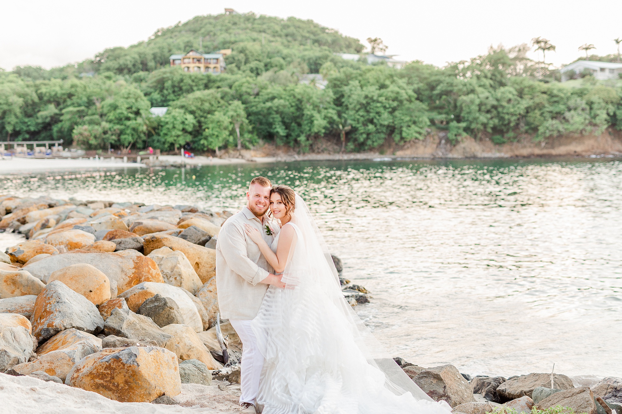 bride and groom lean against rocks in St Lucia