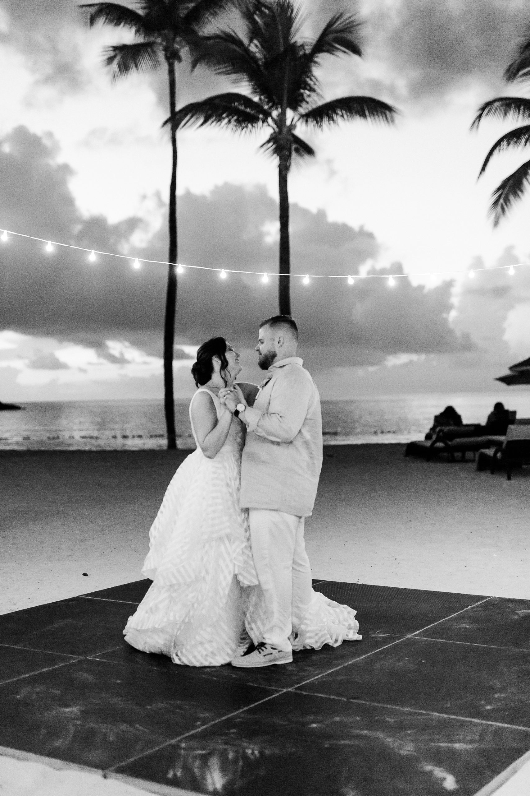romantic first dance under string lights on the beach