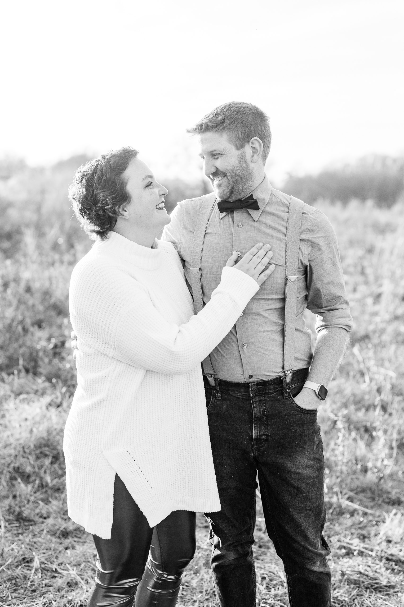 husband and wife pose in field during family photos