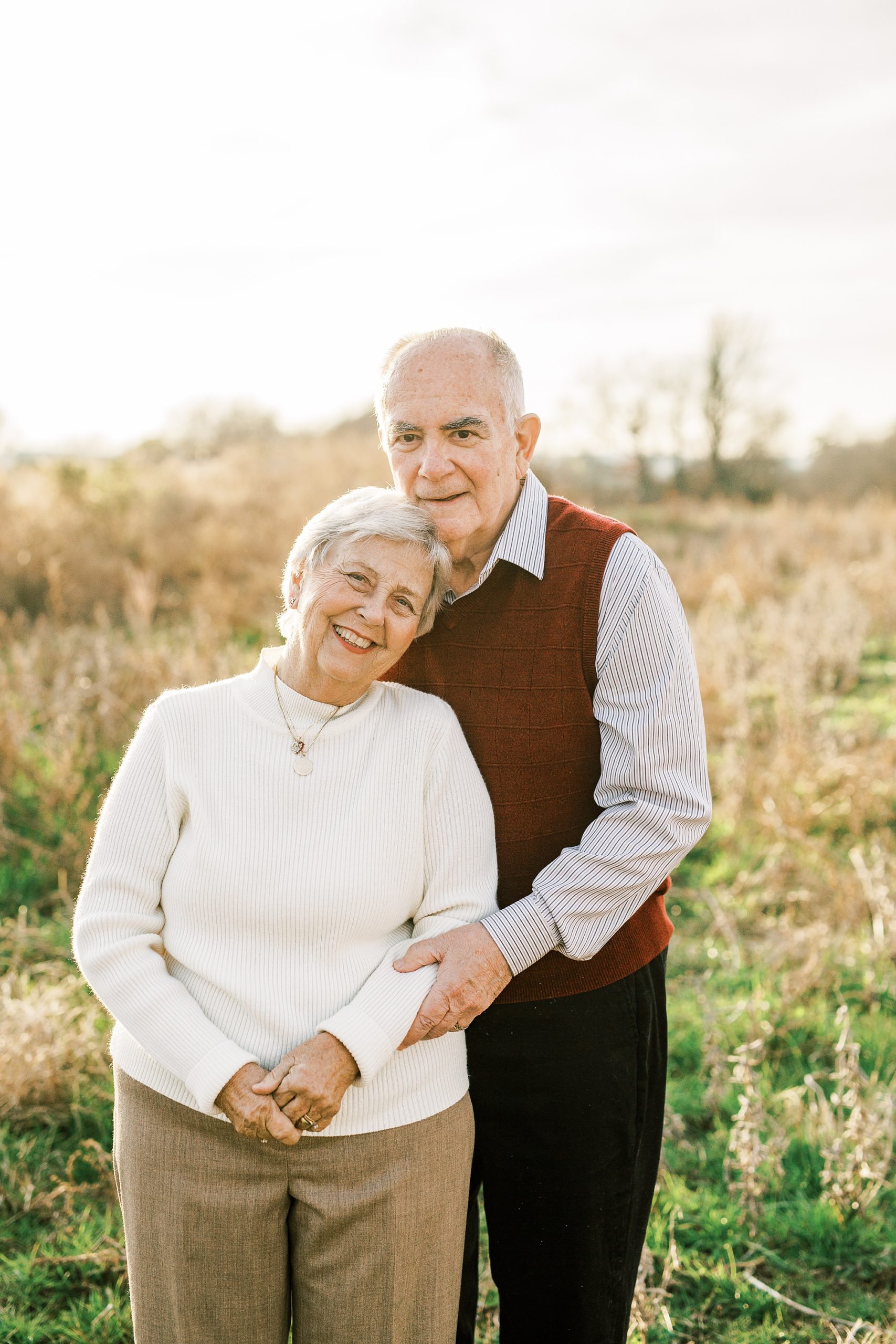 husband and wife pose in field during 50th anniversary photos