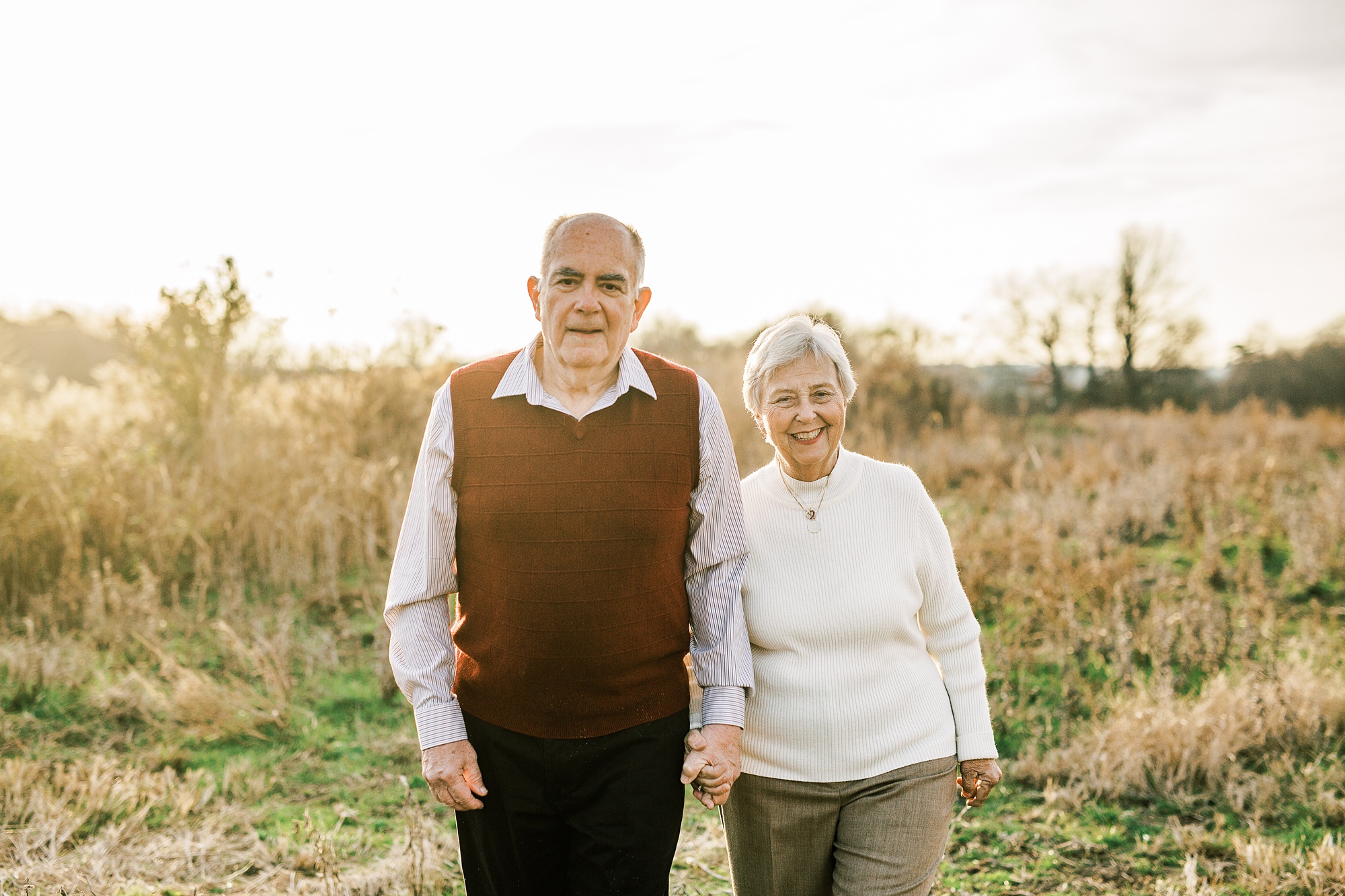 couple walks through field at sunset celebrating 50th anniversary