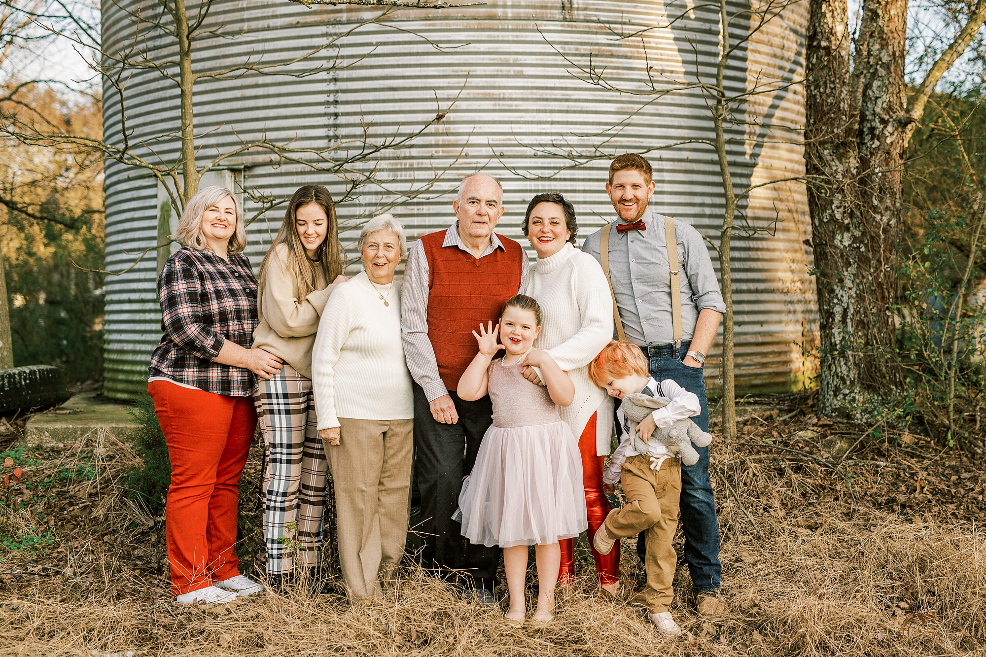 family poses with married couple in front of silo