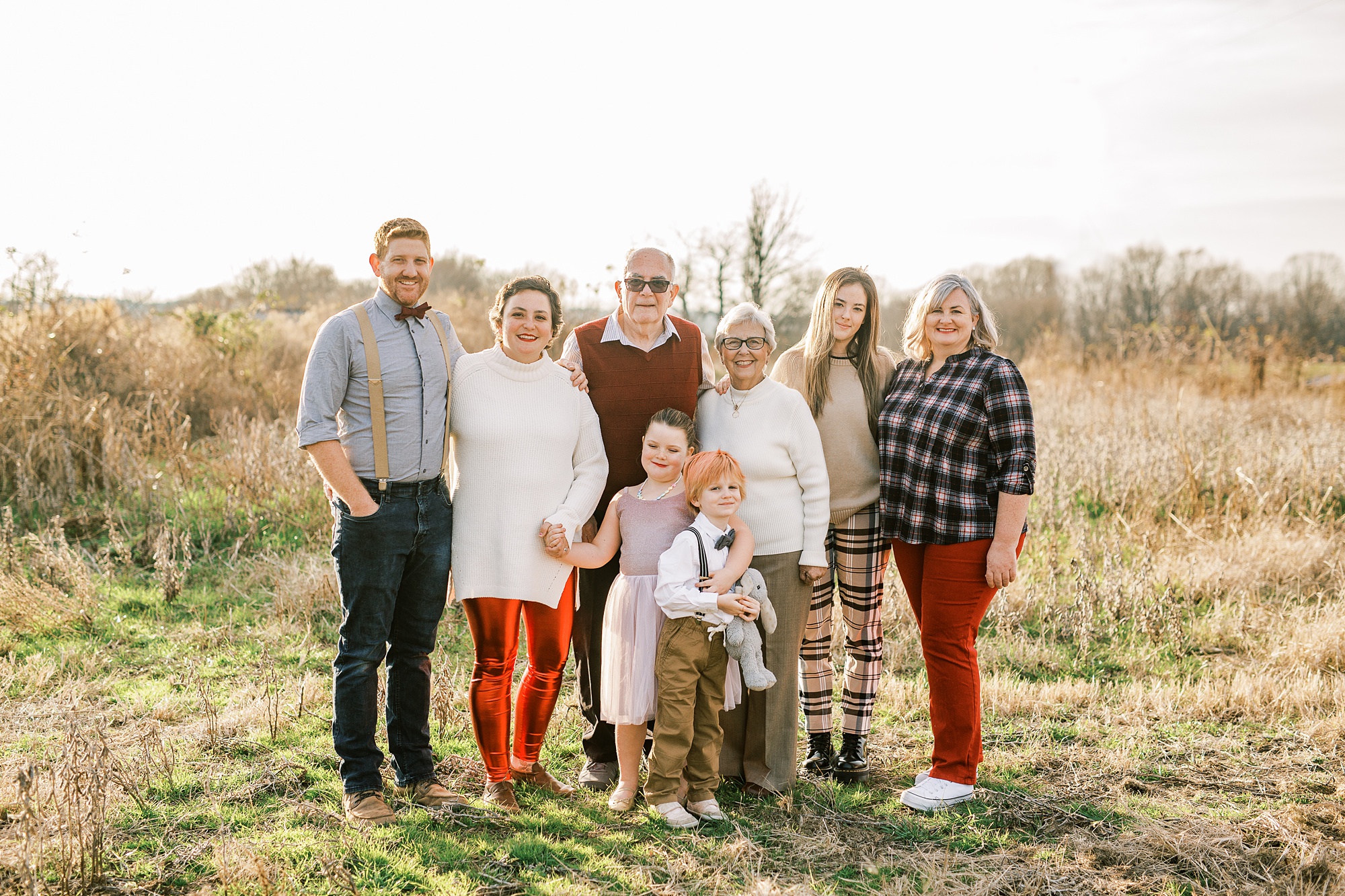 family poses together in field at sunset to celebrate 50th anniversary