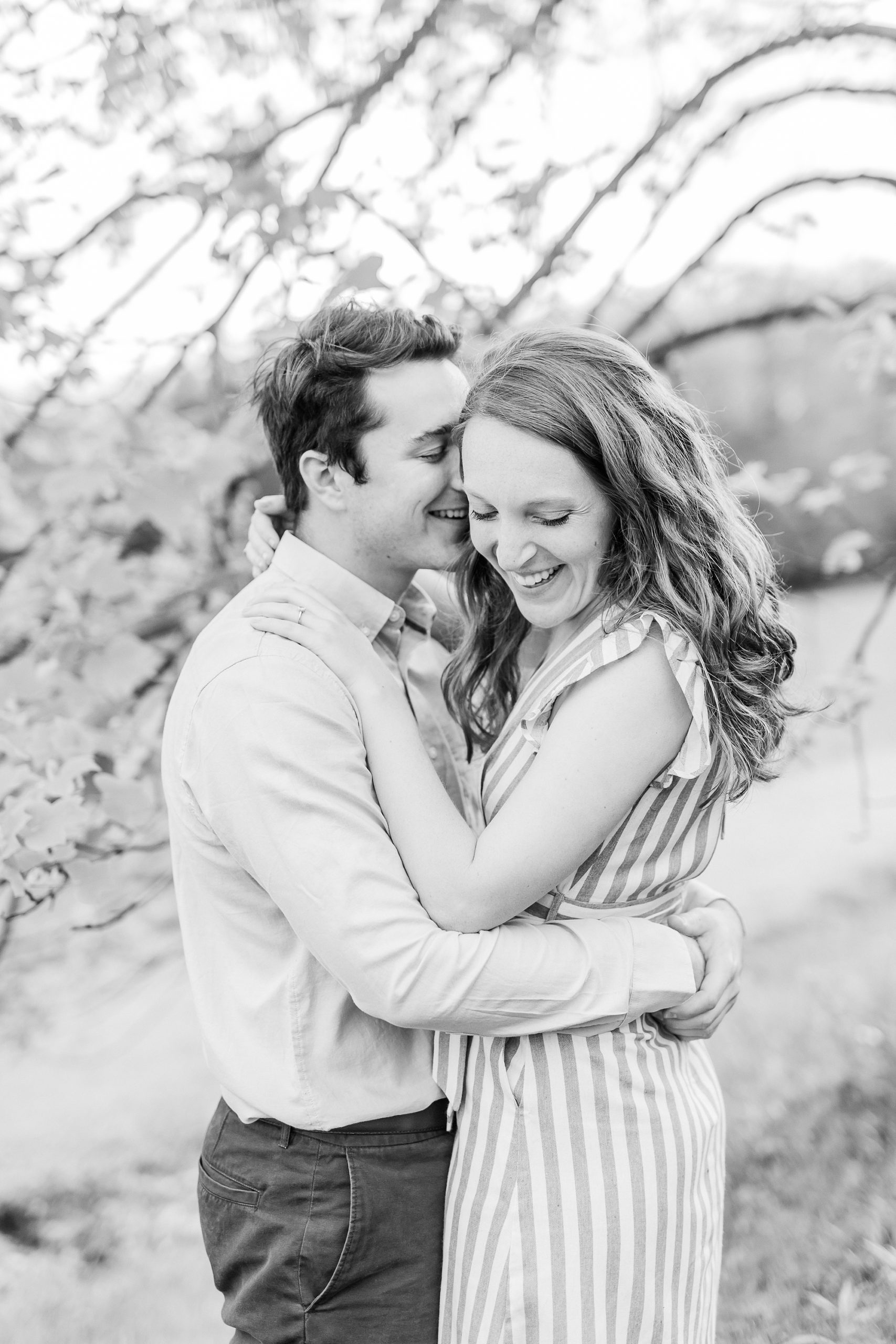 groom makes bride laugh whispering in her ear during spring engagement photos