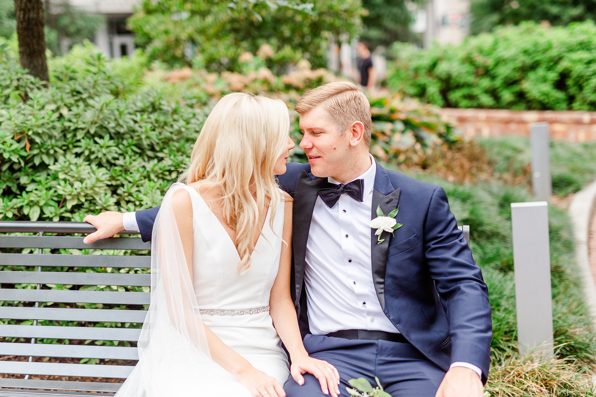 bride and groom sit on bench at Romare Bearden Park