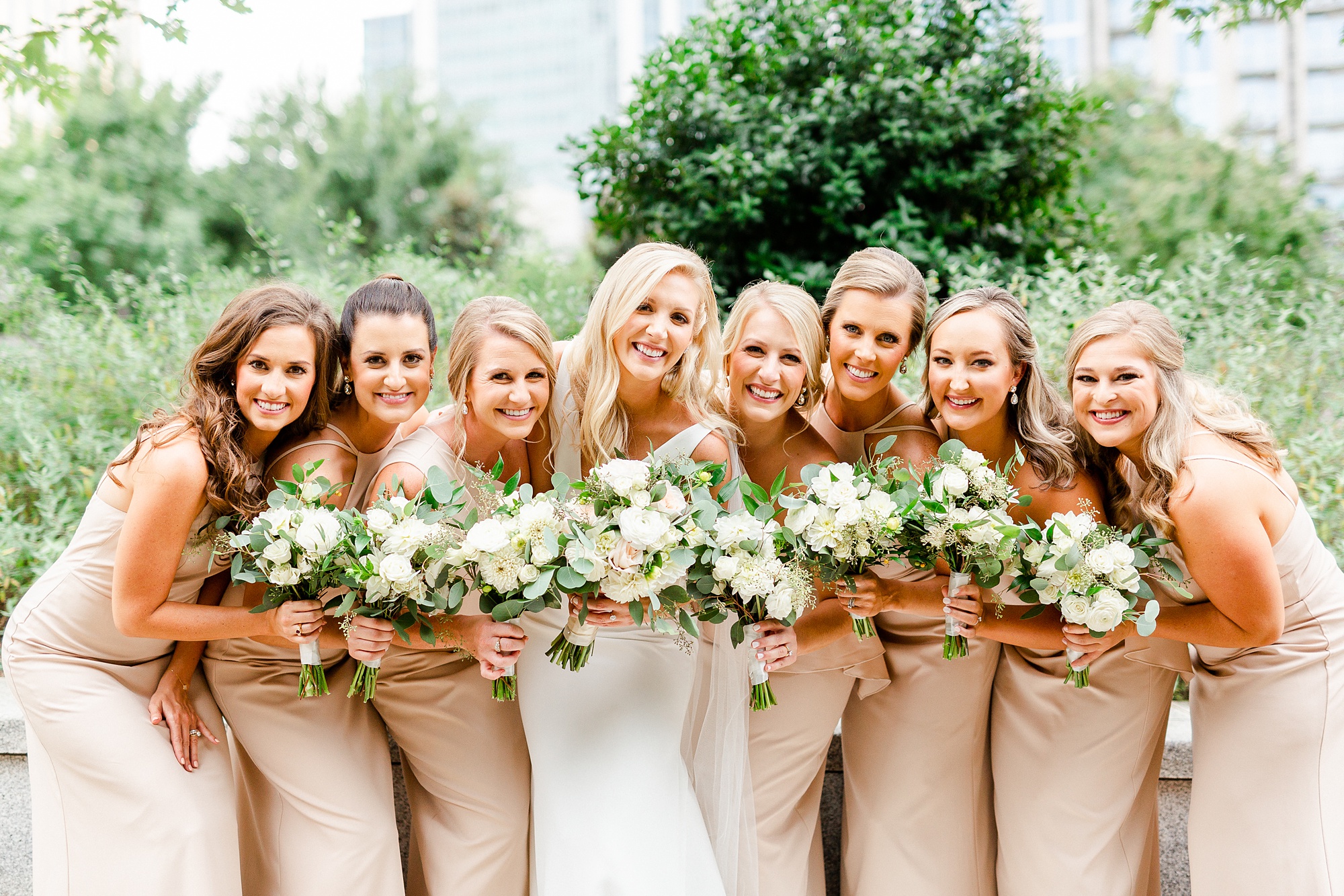 bride and bridesmaids hold bouquets in champagne gowns