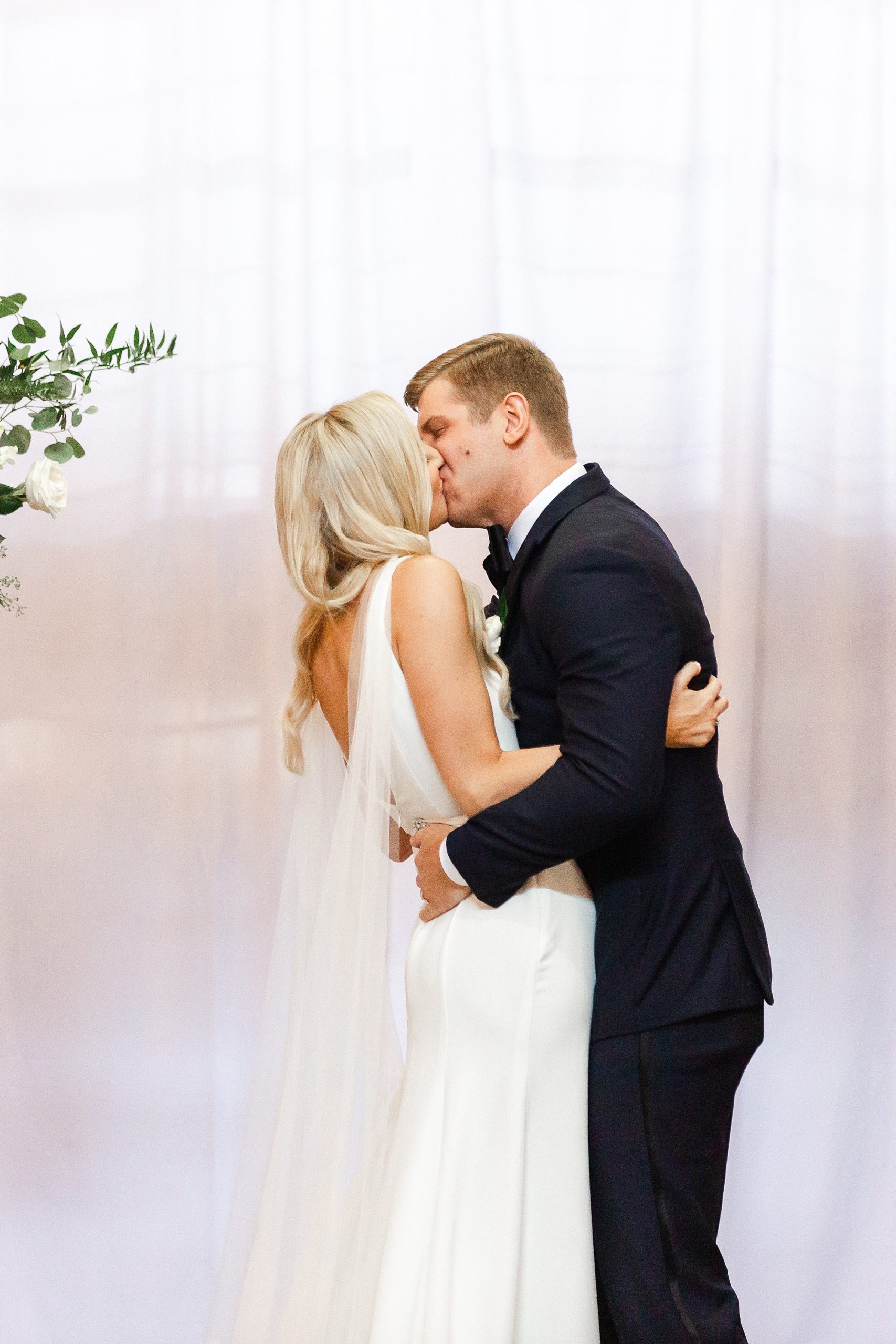 groom kisses bride during Design Center Atrium wedding ceremony