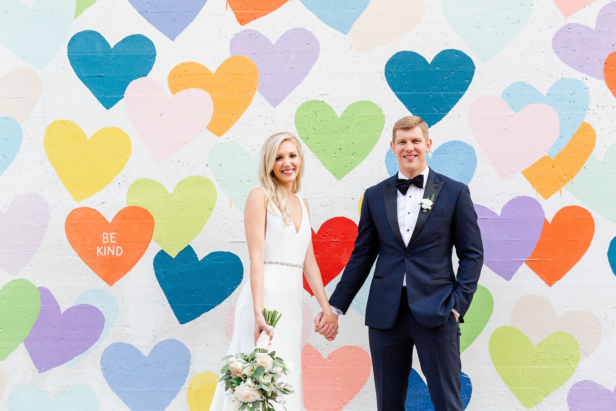 newlyweds pose by colorful heart mural in Charlotte NC