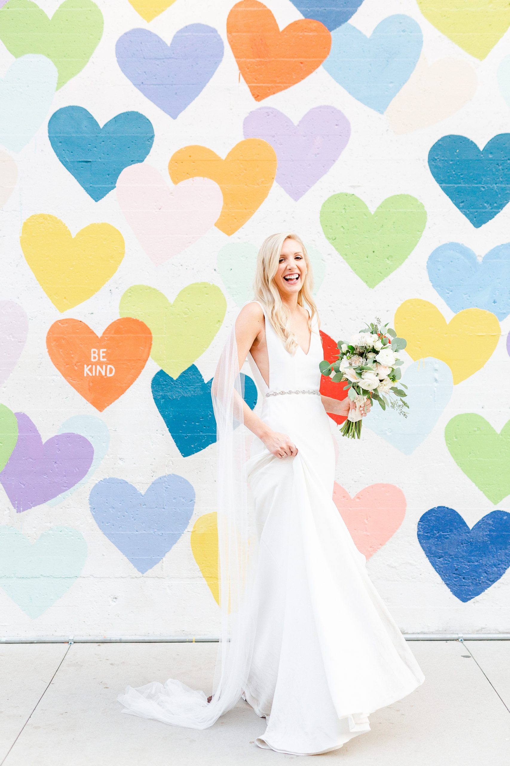 bride twirls wedding gown during portraits by heart mural