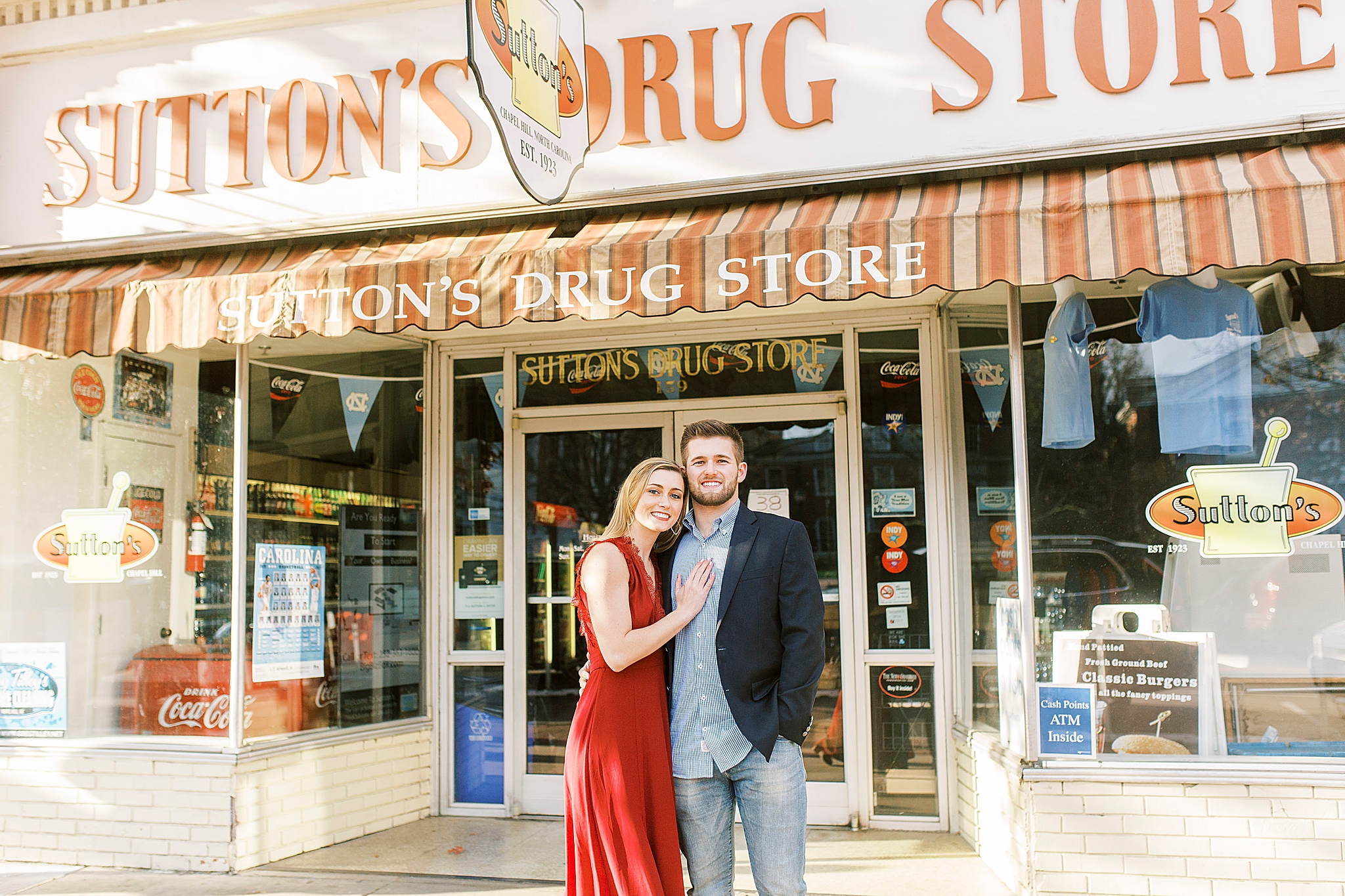 engaged couple poses outside Sutton's Drug Store
