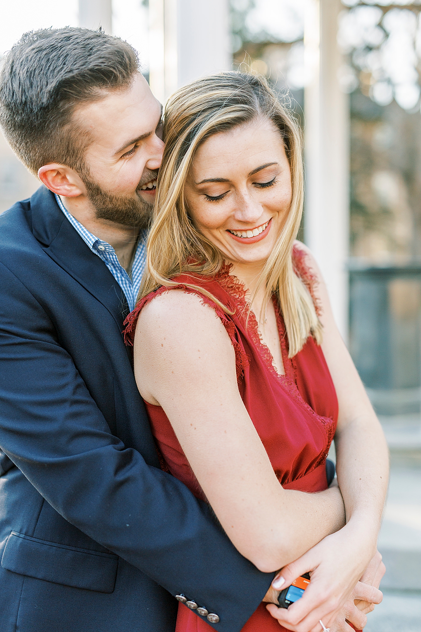 groom whispers in bride's ear during UNC engagement photos