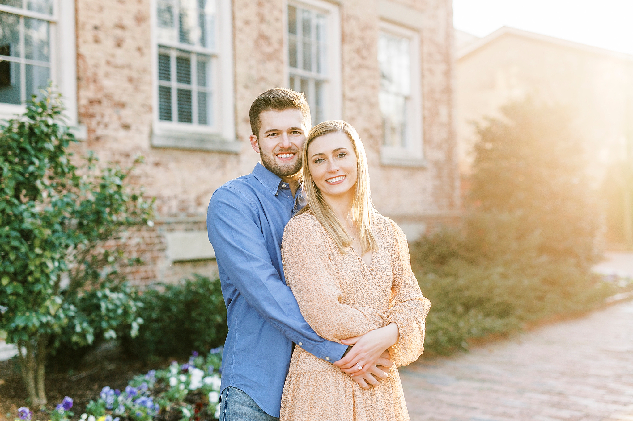 engaged couple poses together by brick buildings on UNC's campus