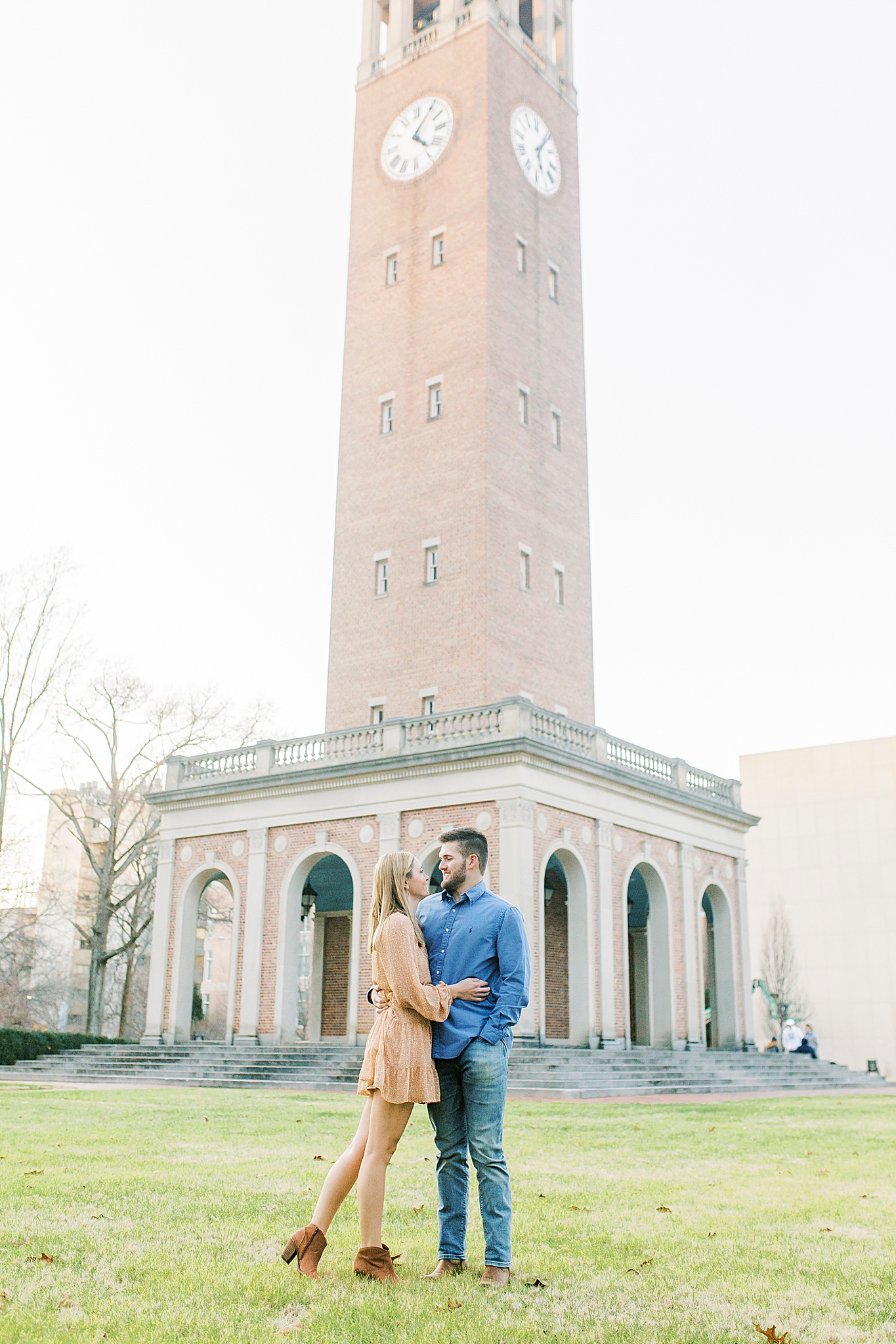 engaged couple poses in front of bell tower at UNC Chapel Hill