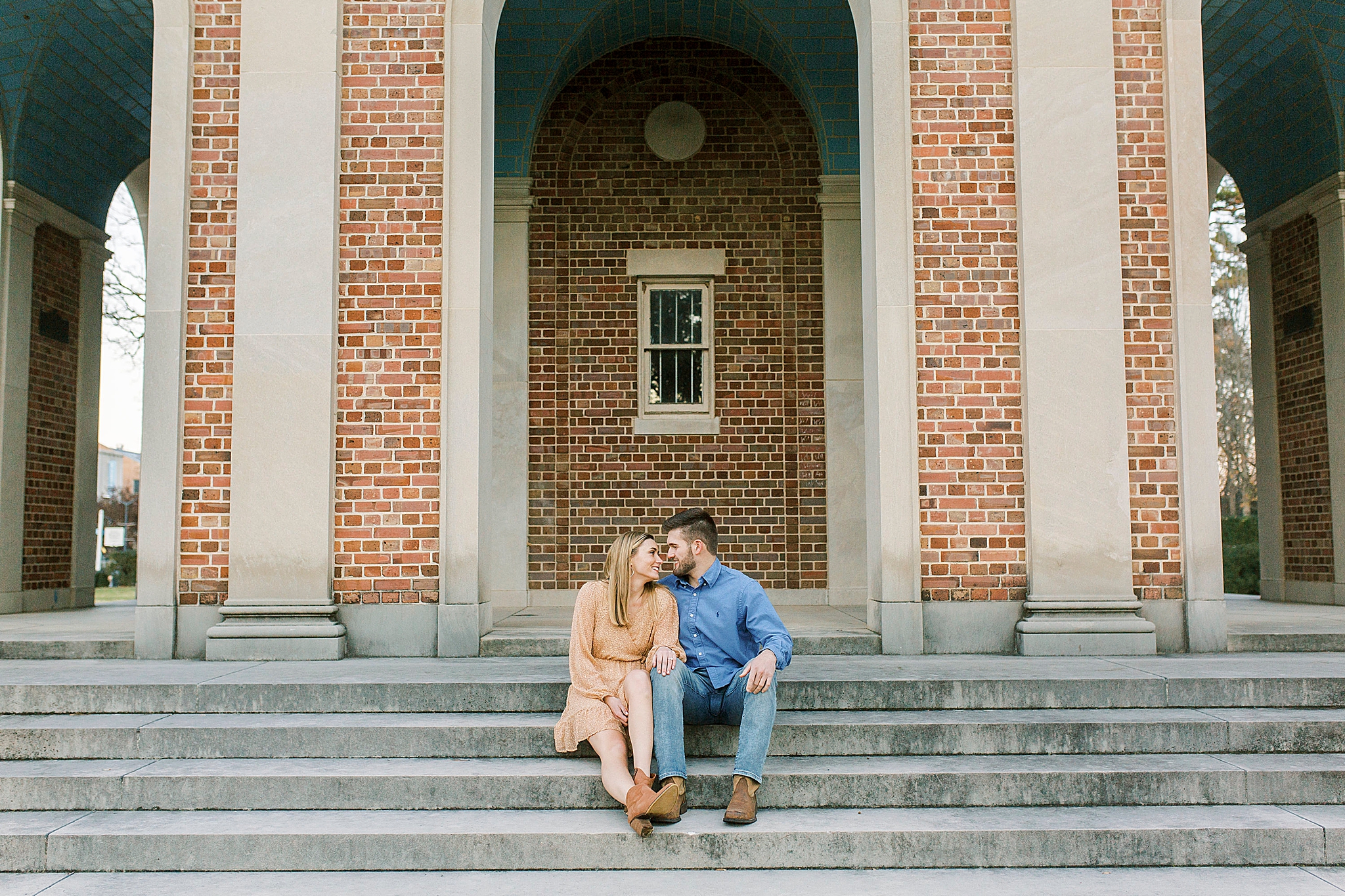 engaged couple sits on steps of UNC bell tower