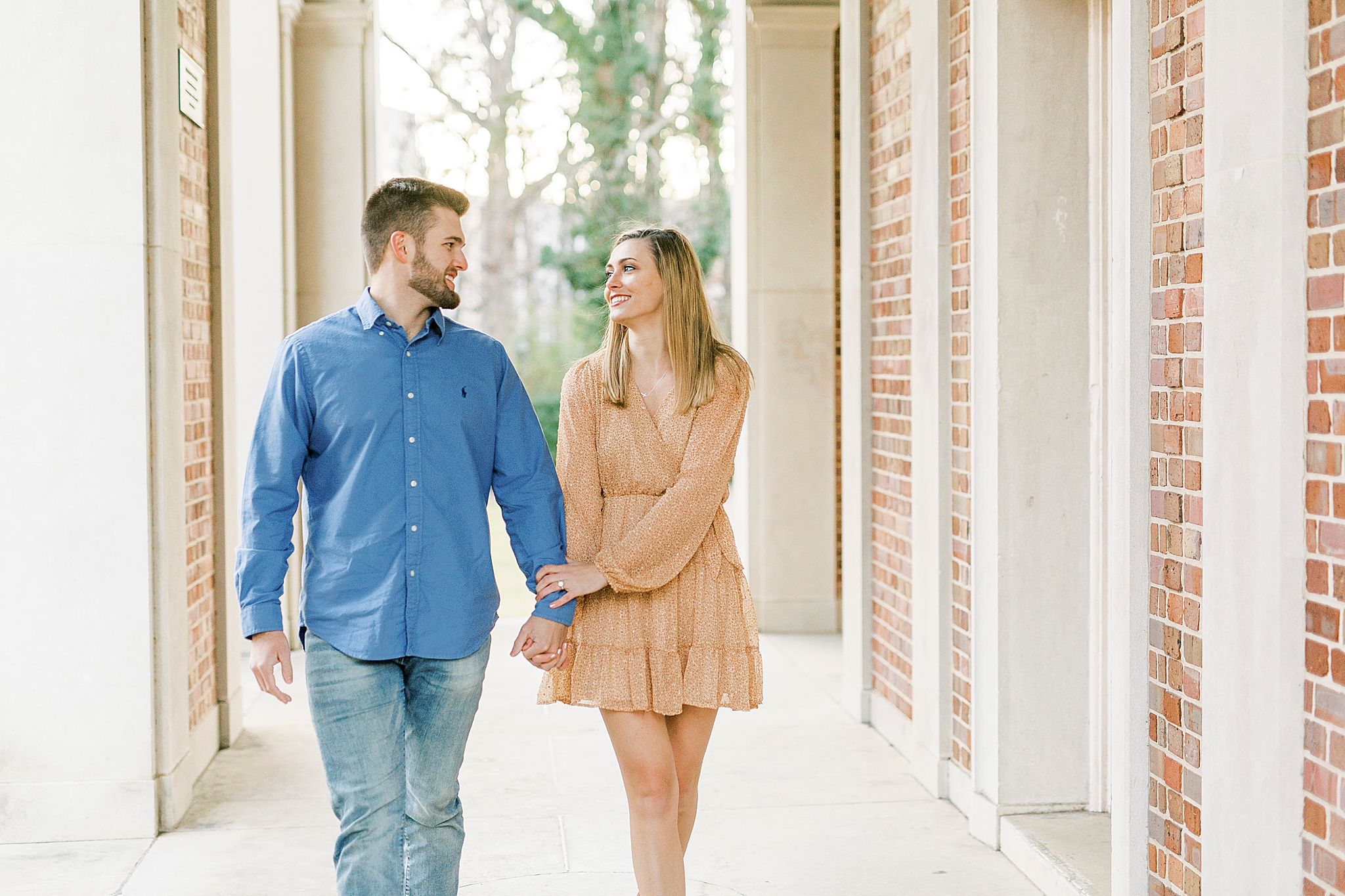 engaged couple holds hands walking through UNC bell tower