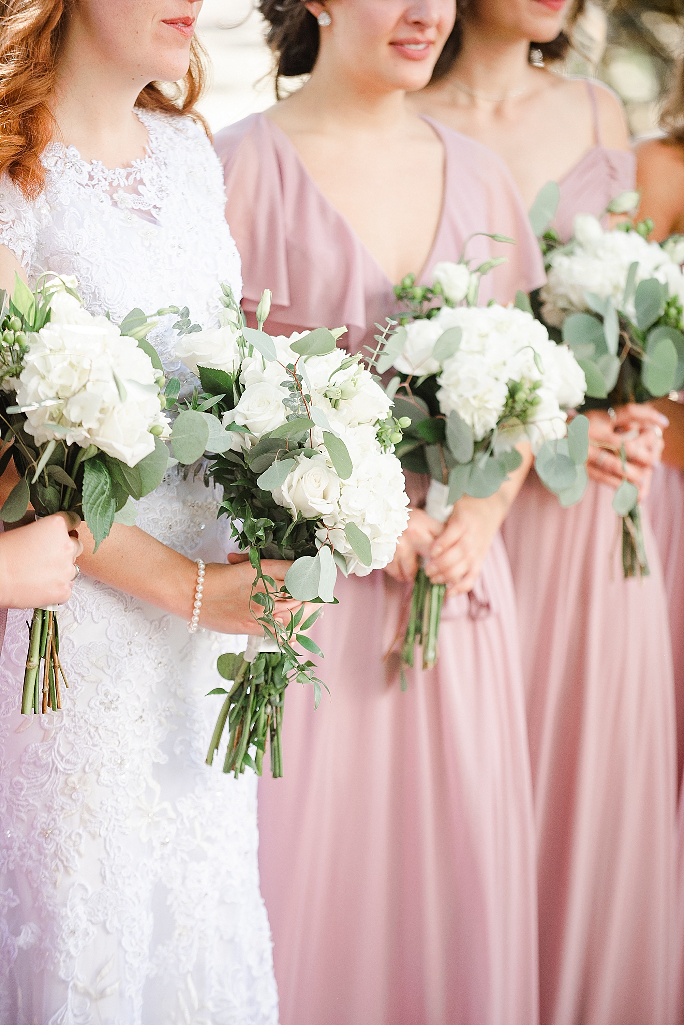 bridesmaids hold white bouquets wearing pink gowns