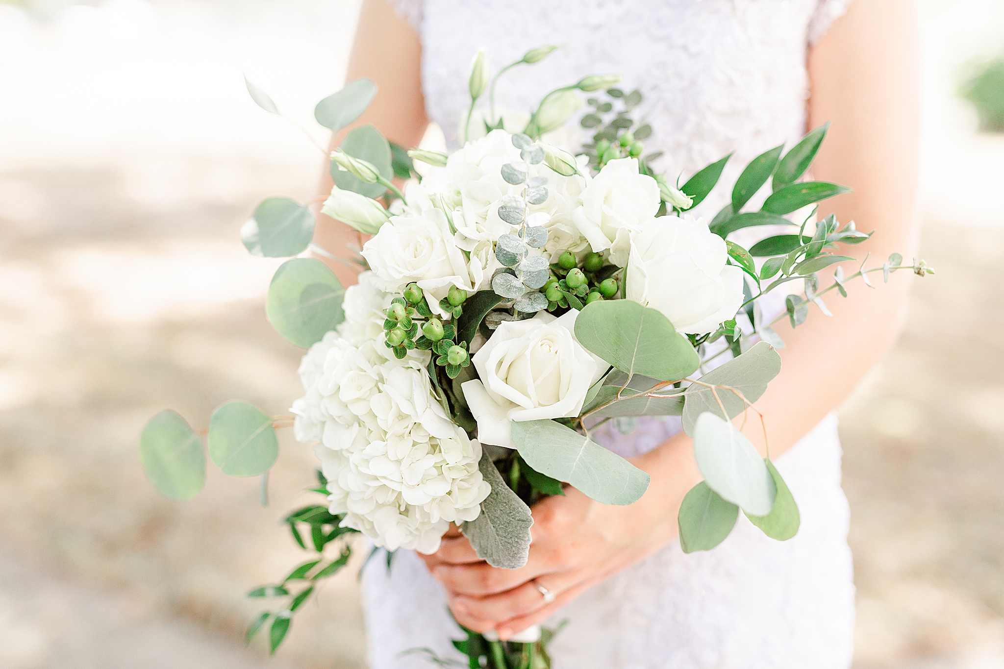 bride holds bouquets of white flowers and eucalyptus leaves
