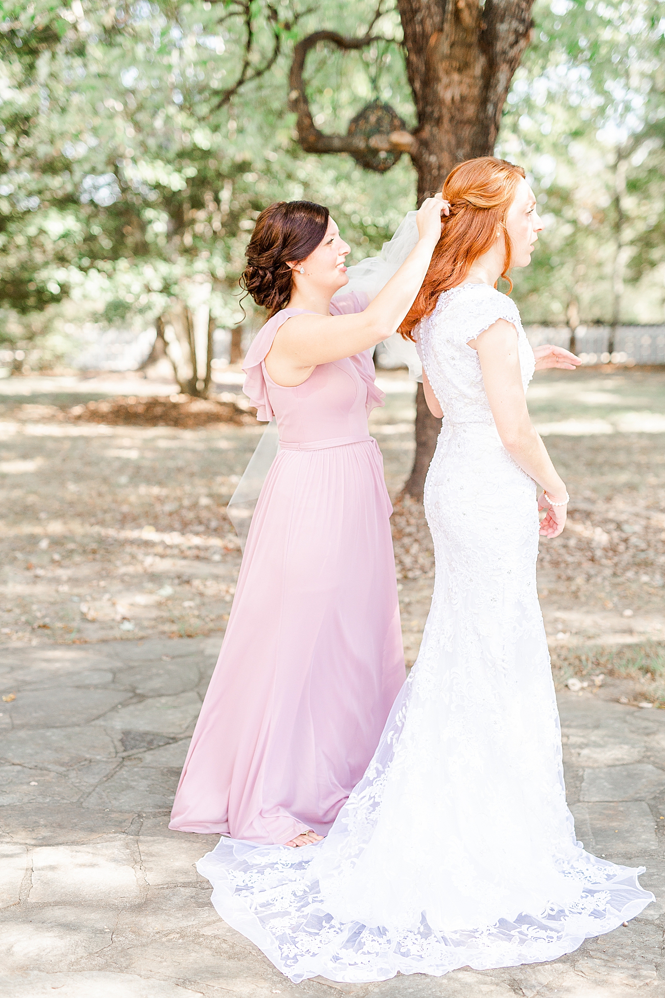 bridesmaid helps attach veil to bride's hair