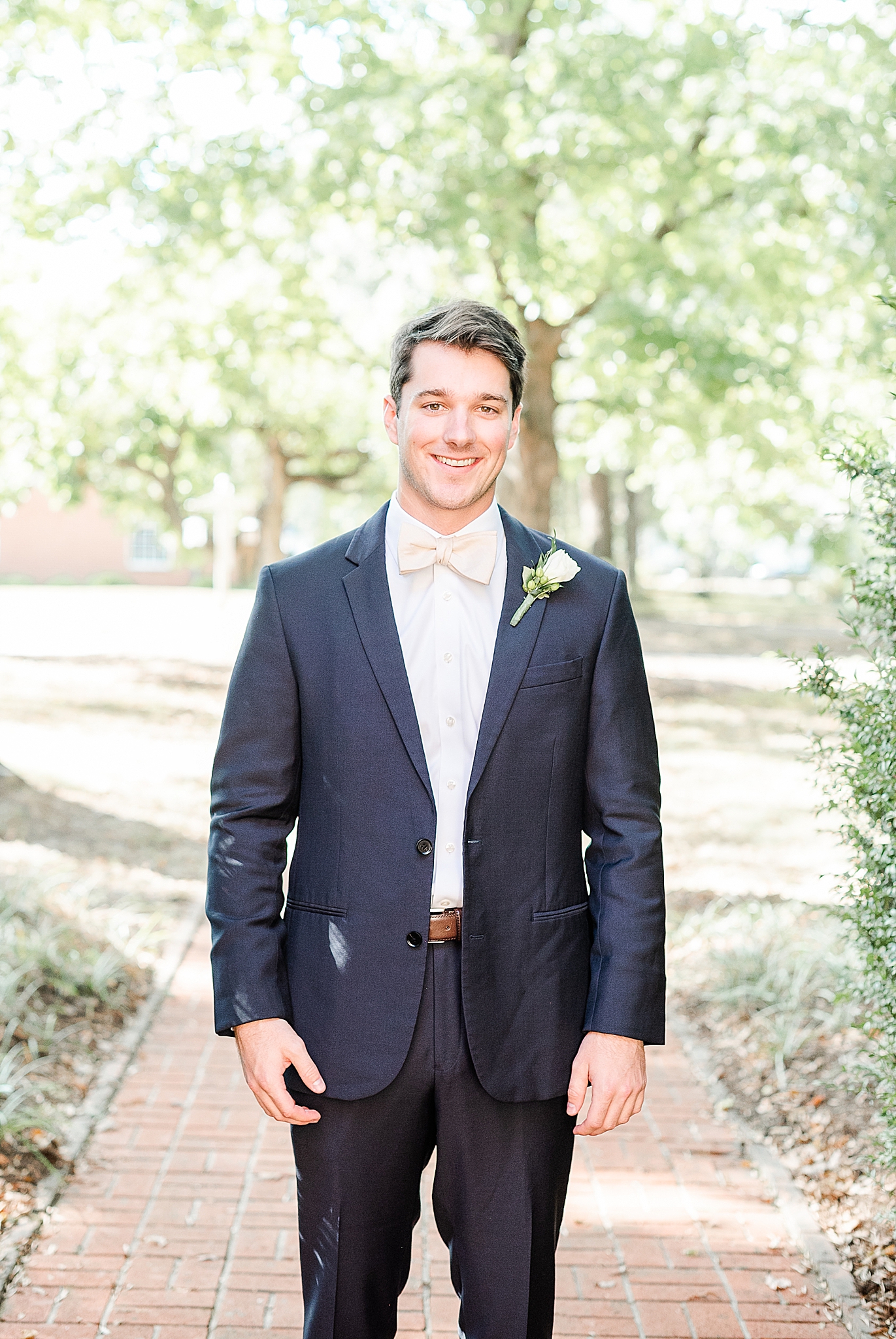 groom in navy suit with ivory boutineere