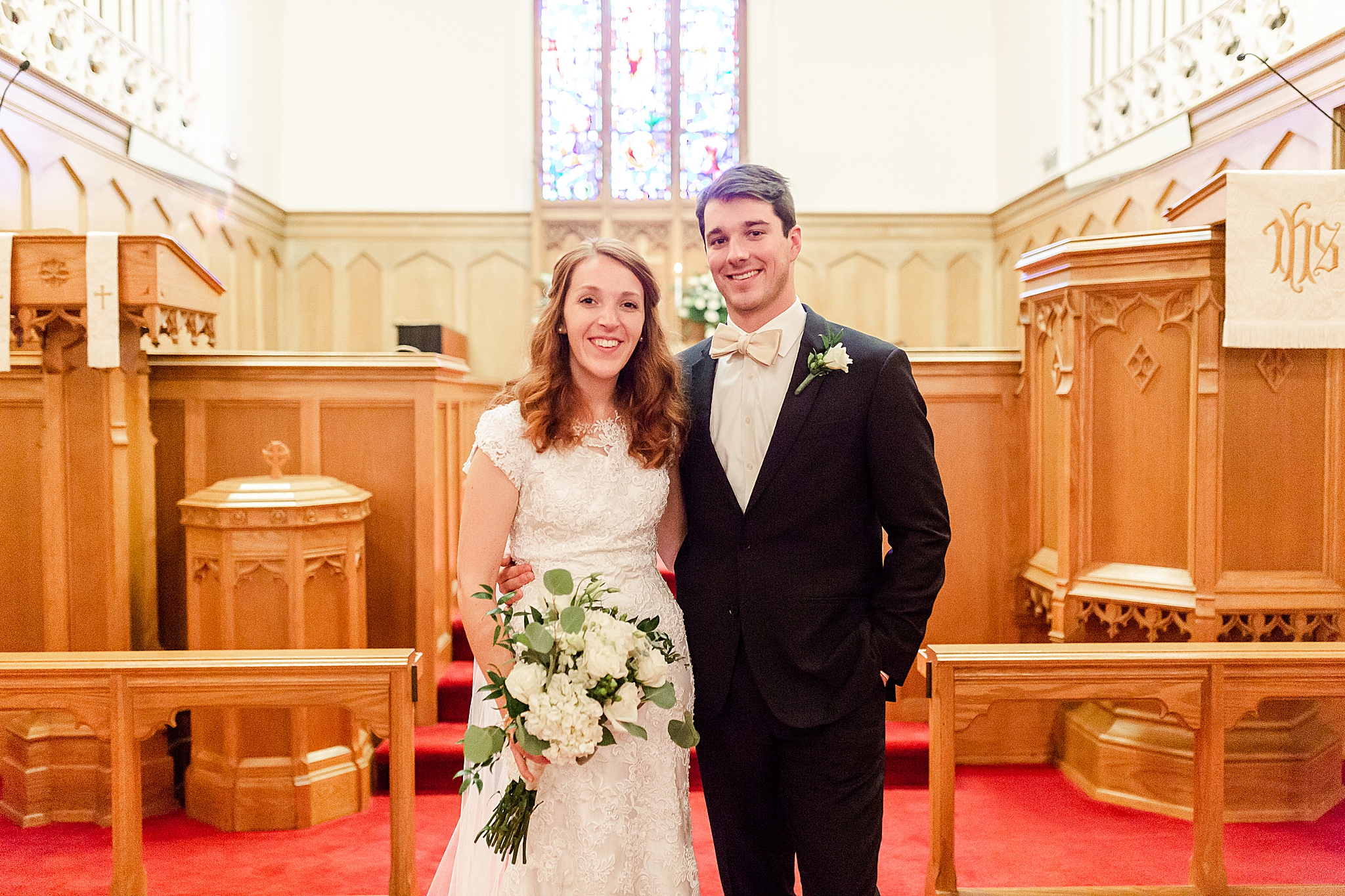 bride and groom pose by altar after traditional classic Southern wedding ceremony in local church