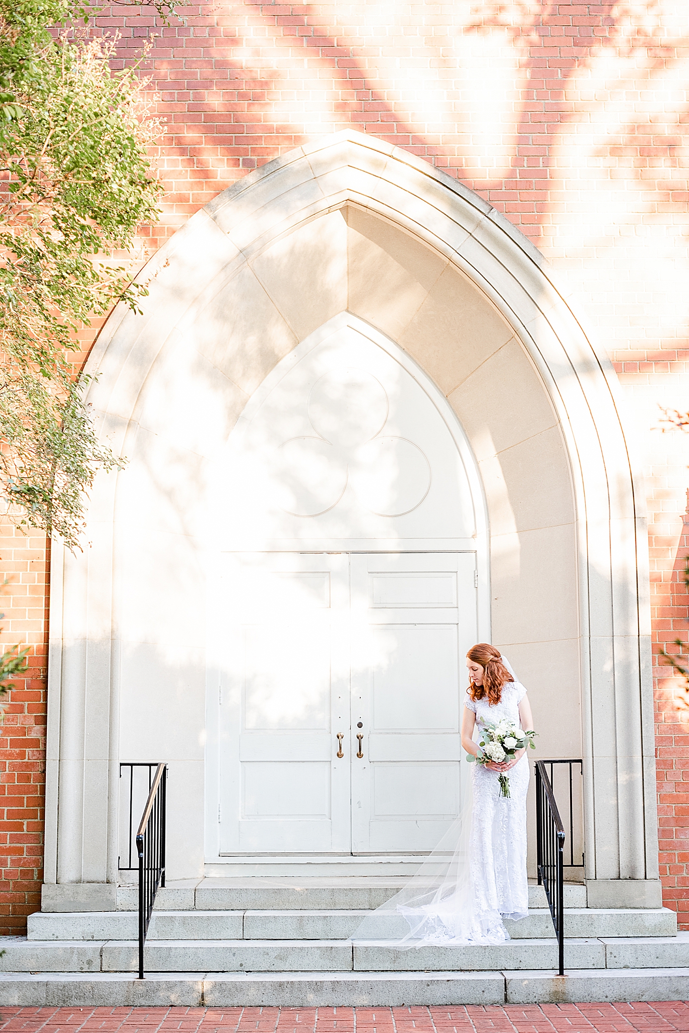 bride poses on church steps holding bouquet and looking over shoulder
