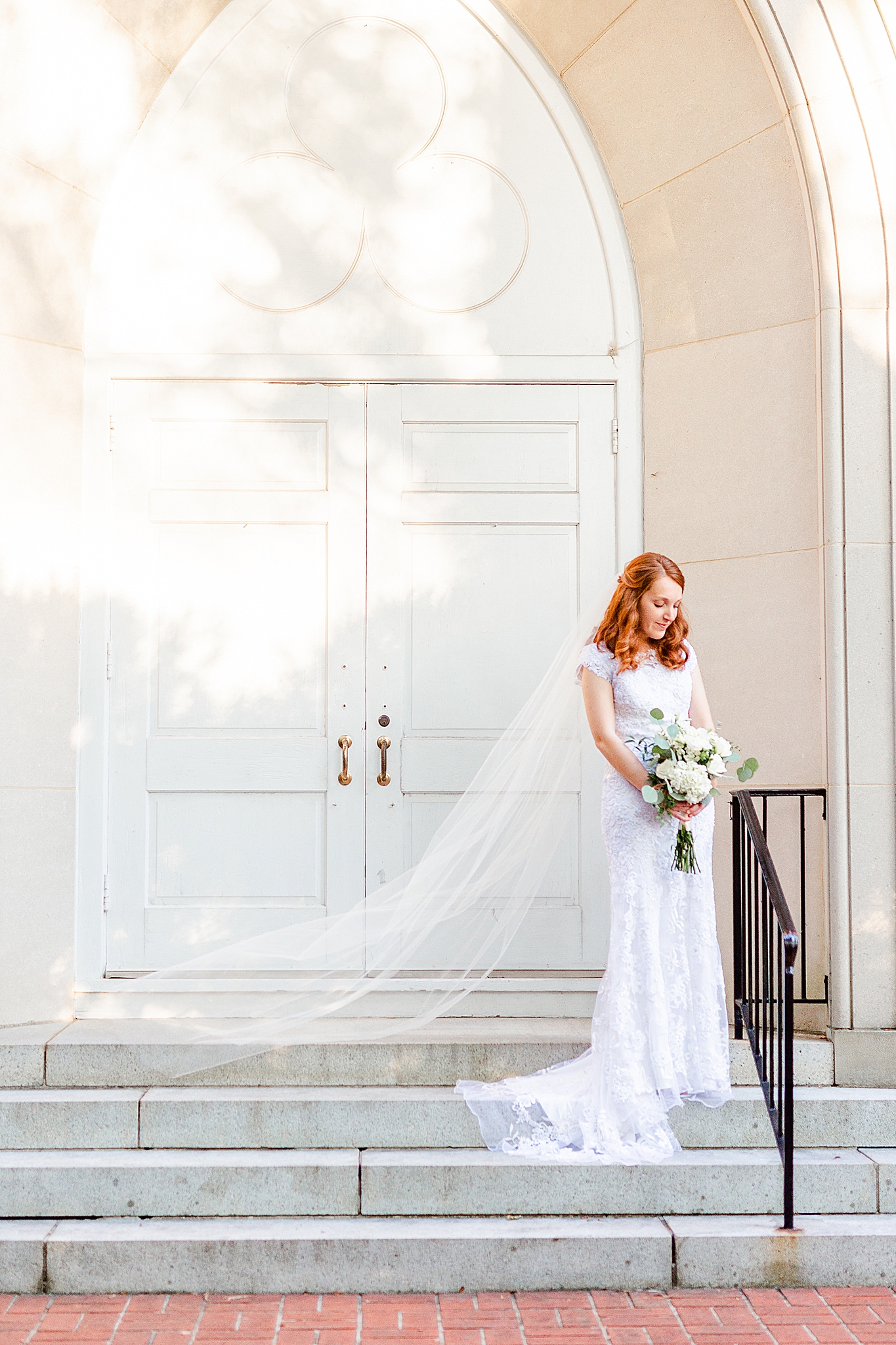 bride holds bouquet and looks down on church steps