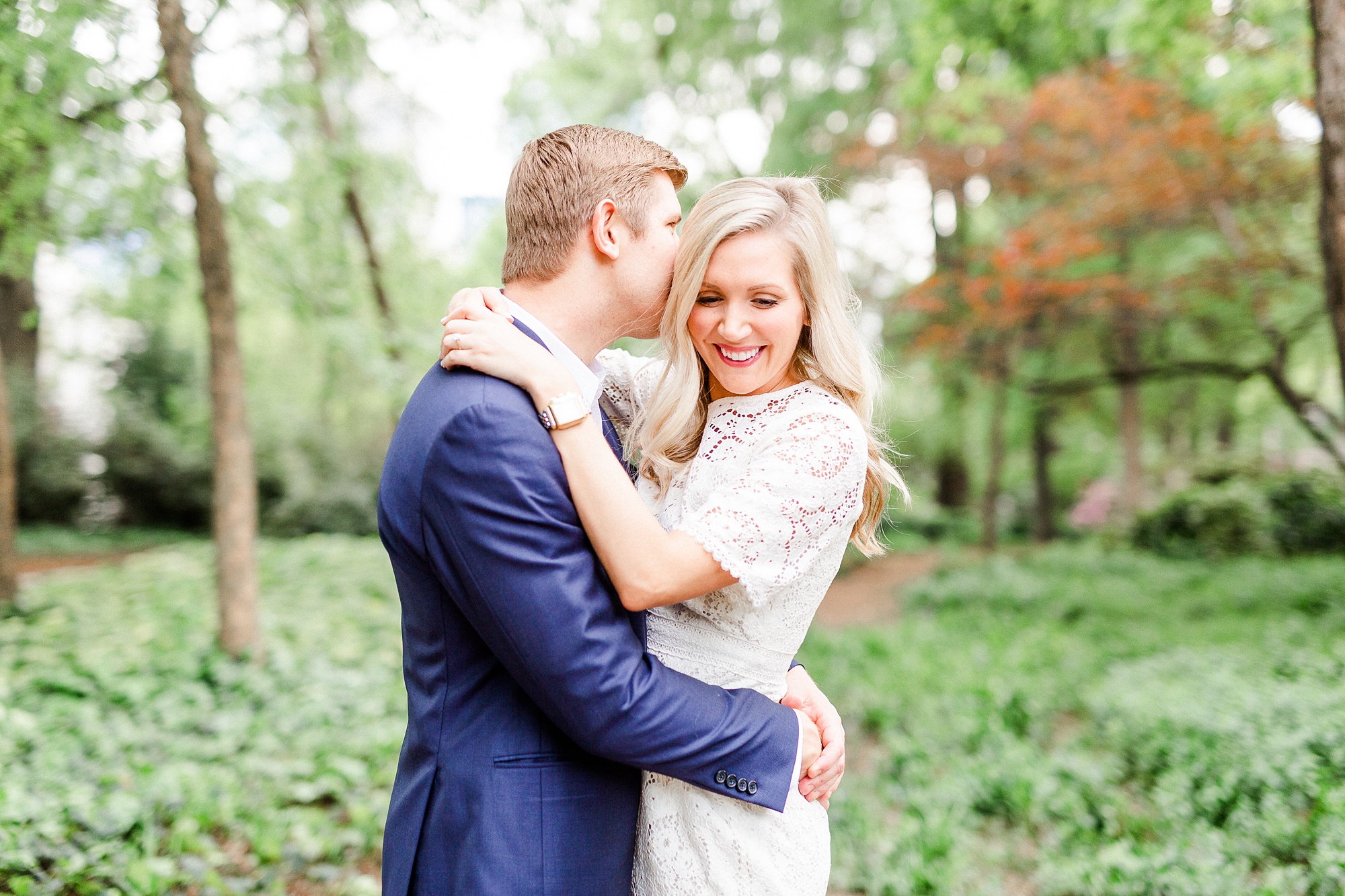 groom whispers in bride's ear during stylish Charlotte engagement session