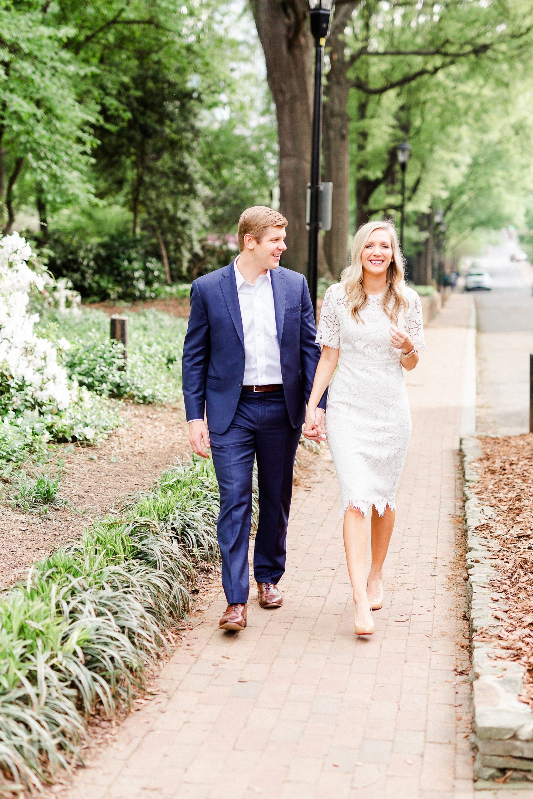 bride and groom hold hands walking down sidewalk in Charlotte