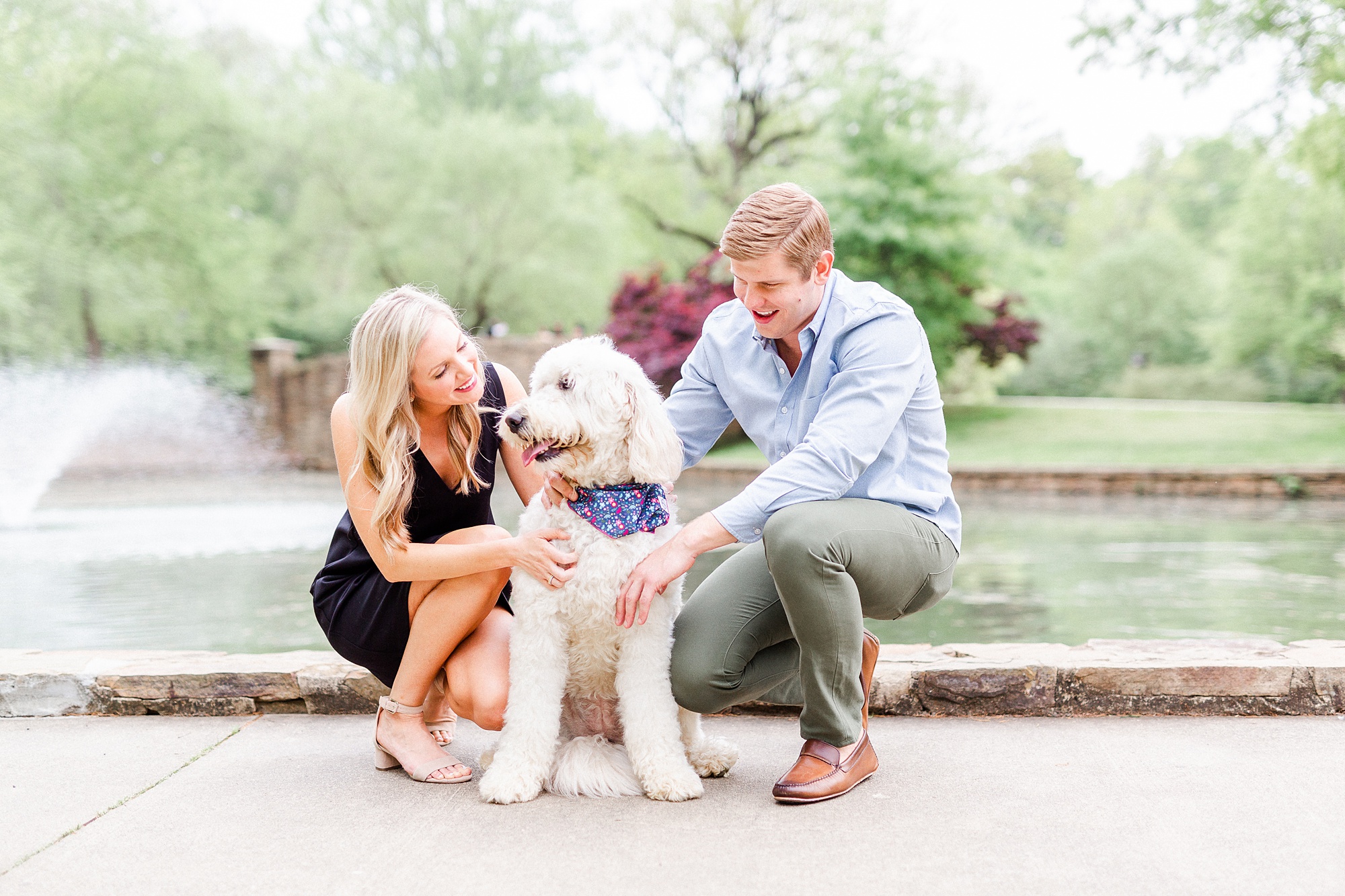 engaged couple poses by Freedom Park pond with dog