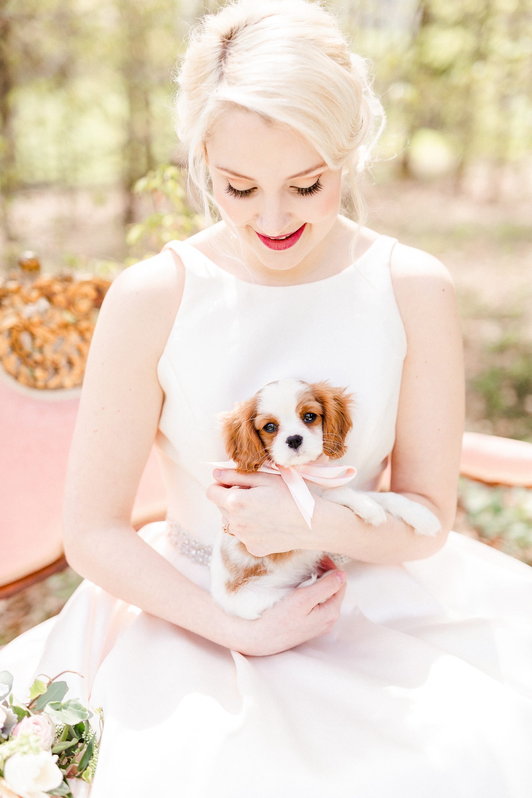bride holds puppy dog sitting on pink couch