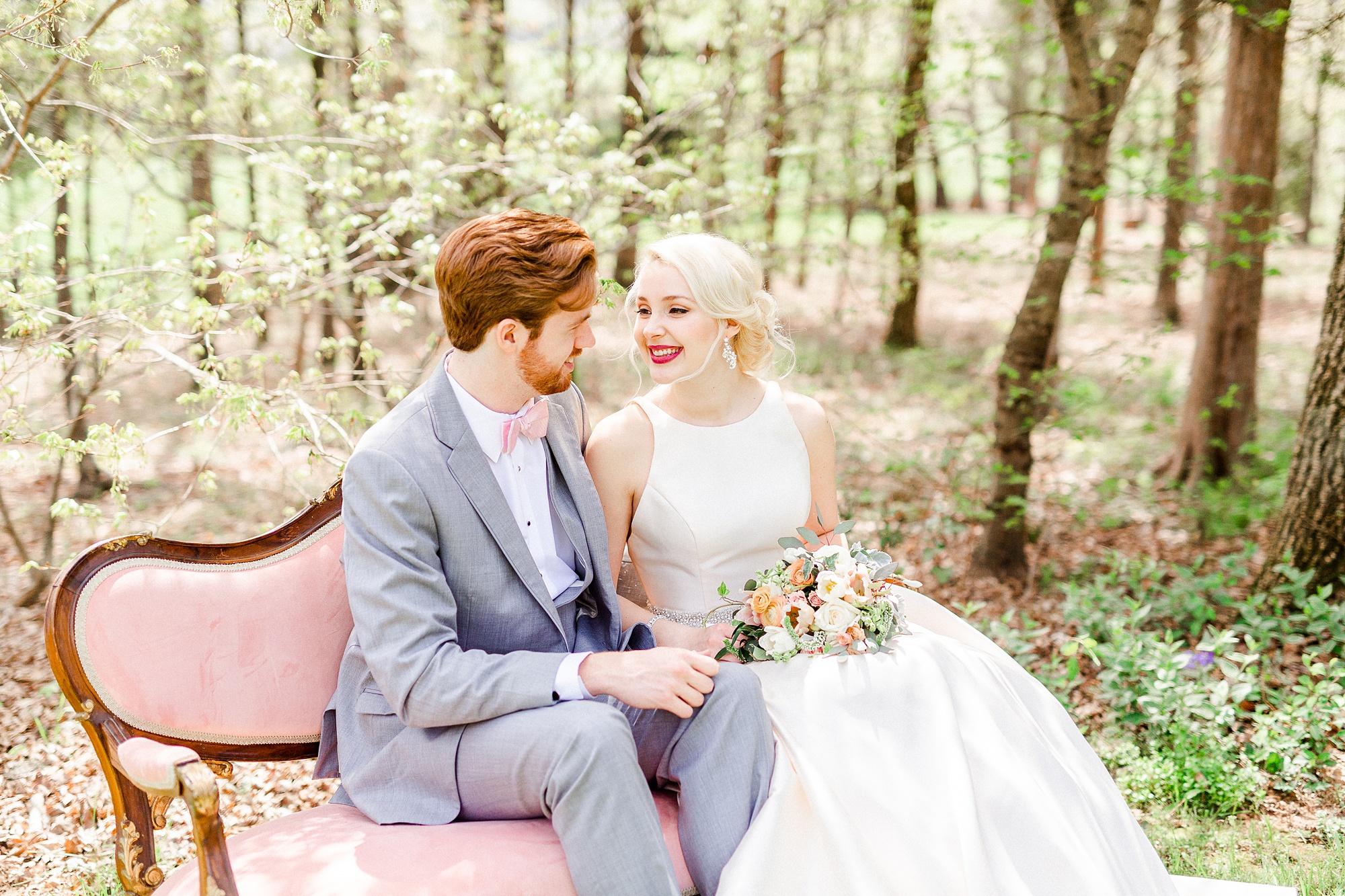 bride and groom smile at each other on pink couch at Carolina Country Weddings