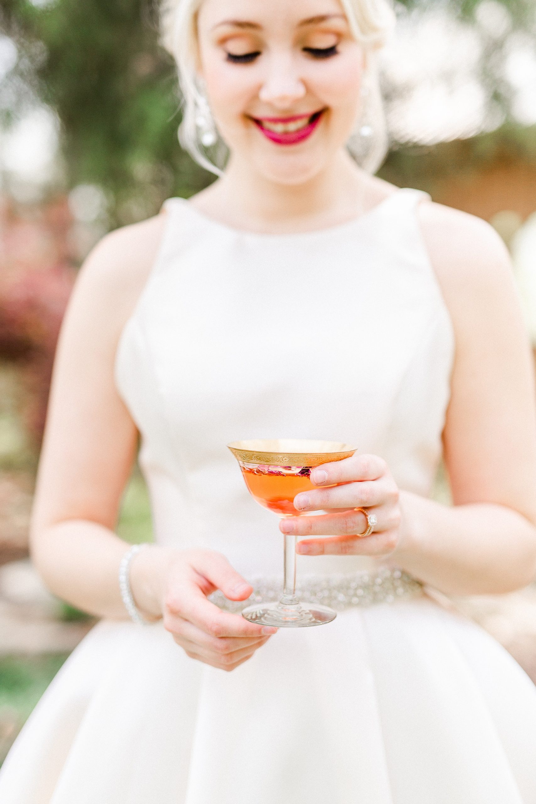 bride holds spring cocktail in vintage glass