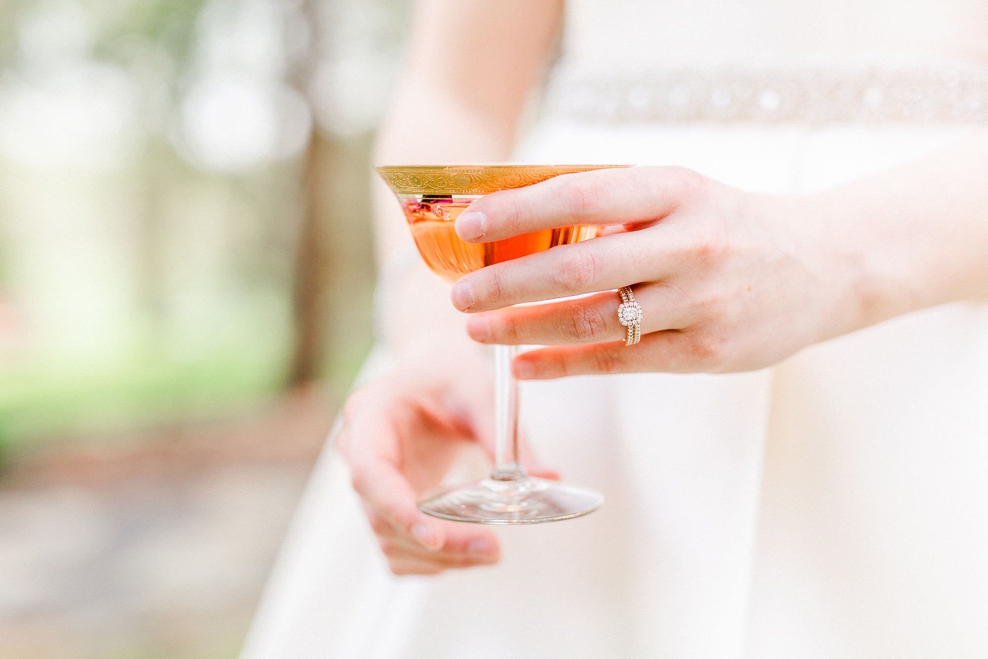 bride holds cocktail showing off wedding ring
