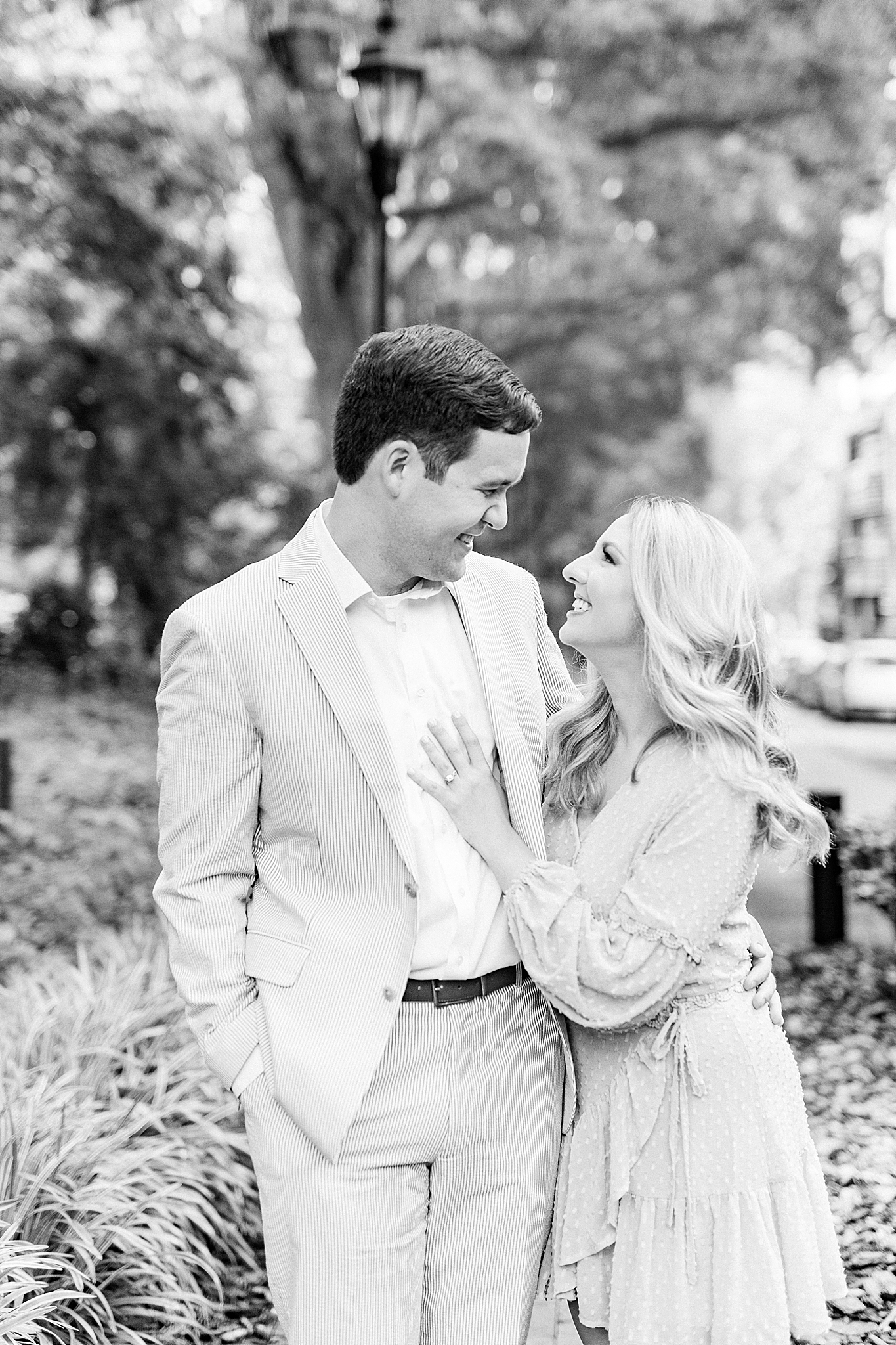 bride lays hand on groom's chest during uptown Charlotte engagement photos