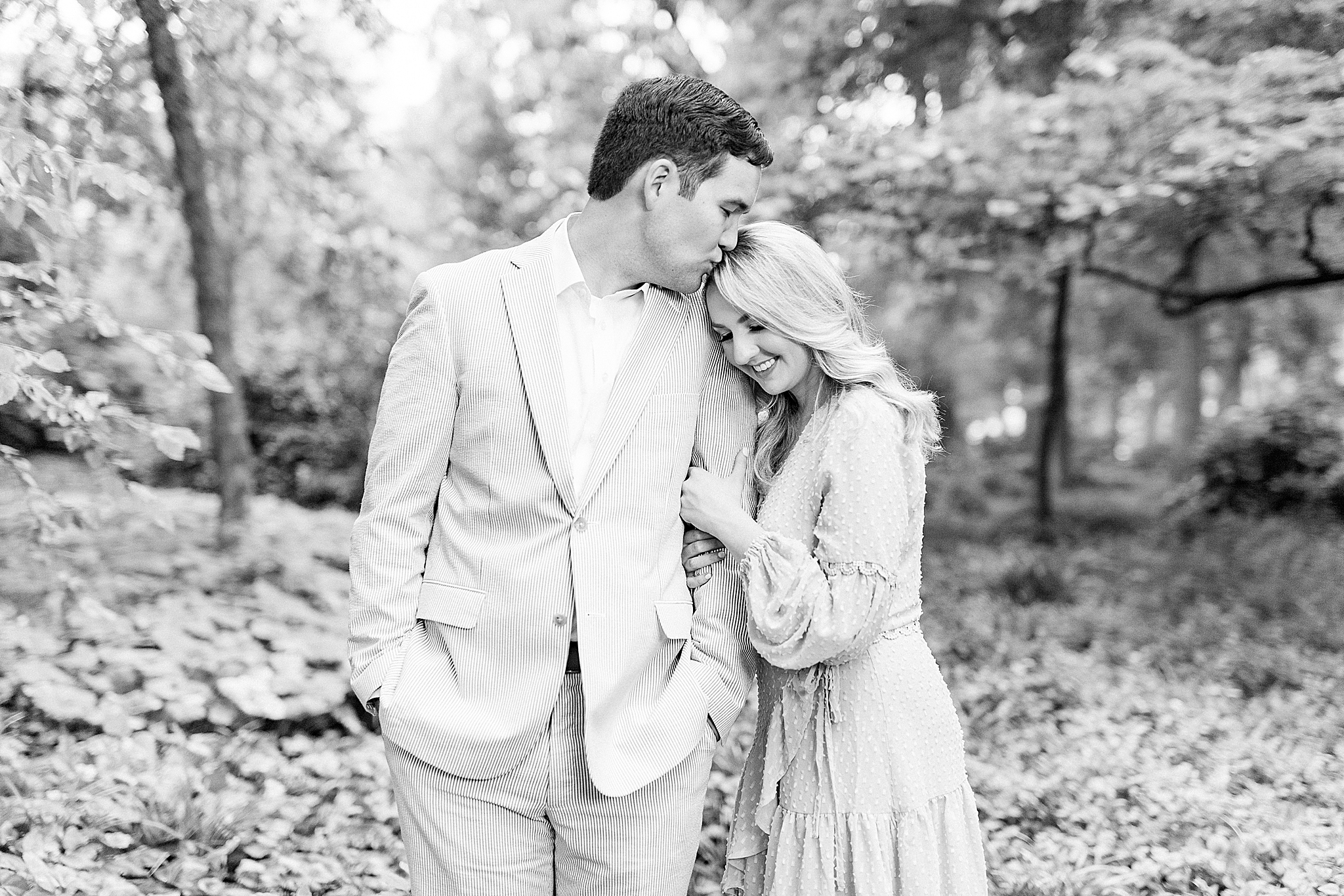 bride leans against groom's arm during uptown Charlotte engagement photos