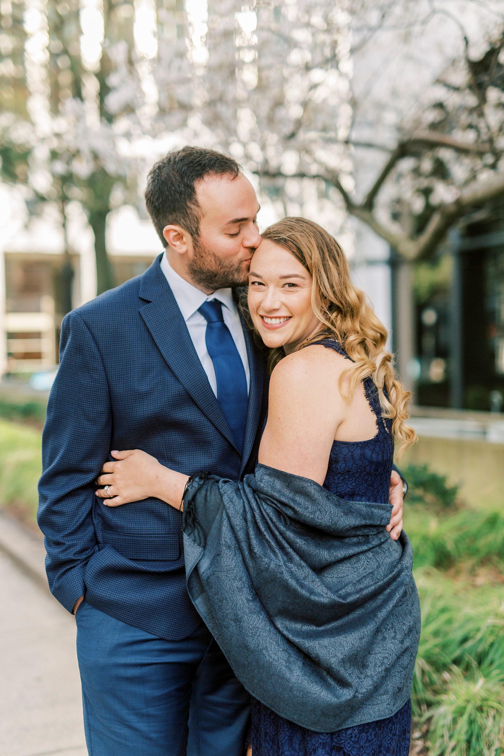 groom kisses bride's forehead in Uptown Charlotte during engagement photos