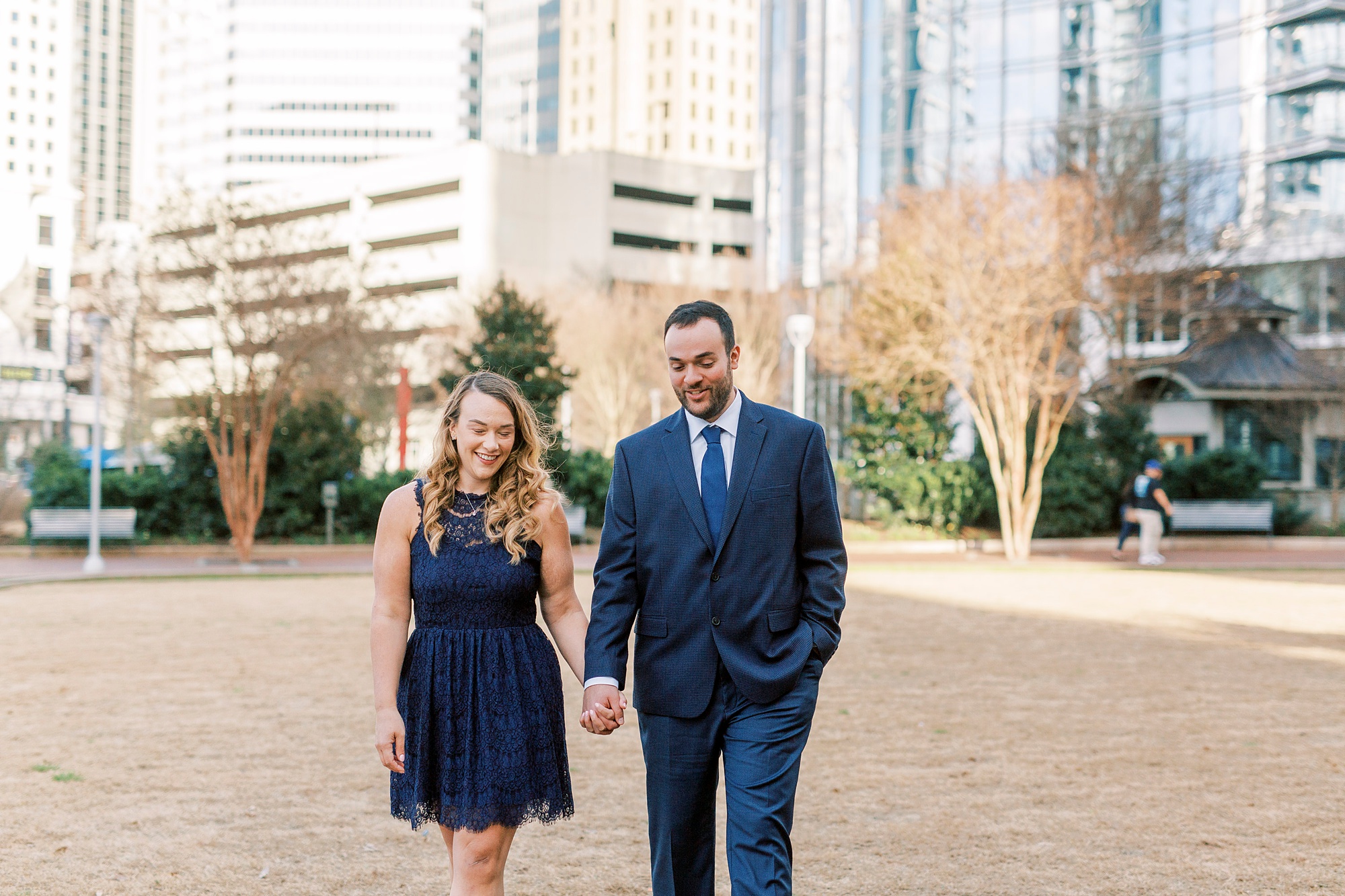 bride and groom walk through Uptown Charlotte during engagement photos