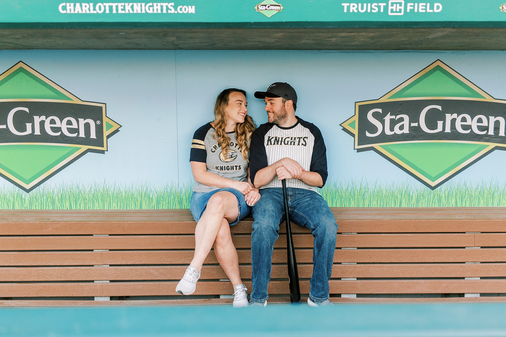 bride and groom sit inside dug out at Truist Field